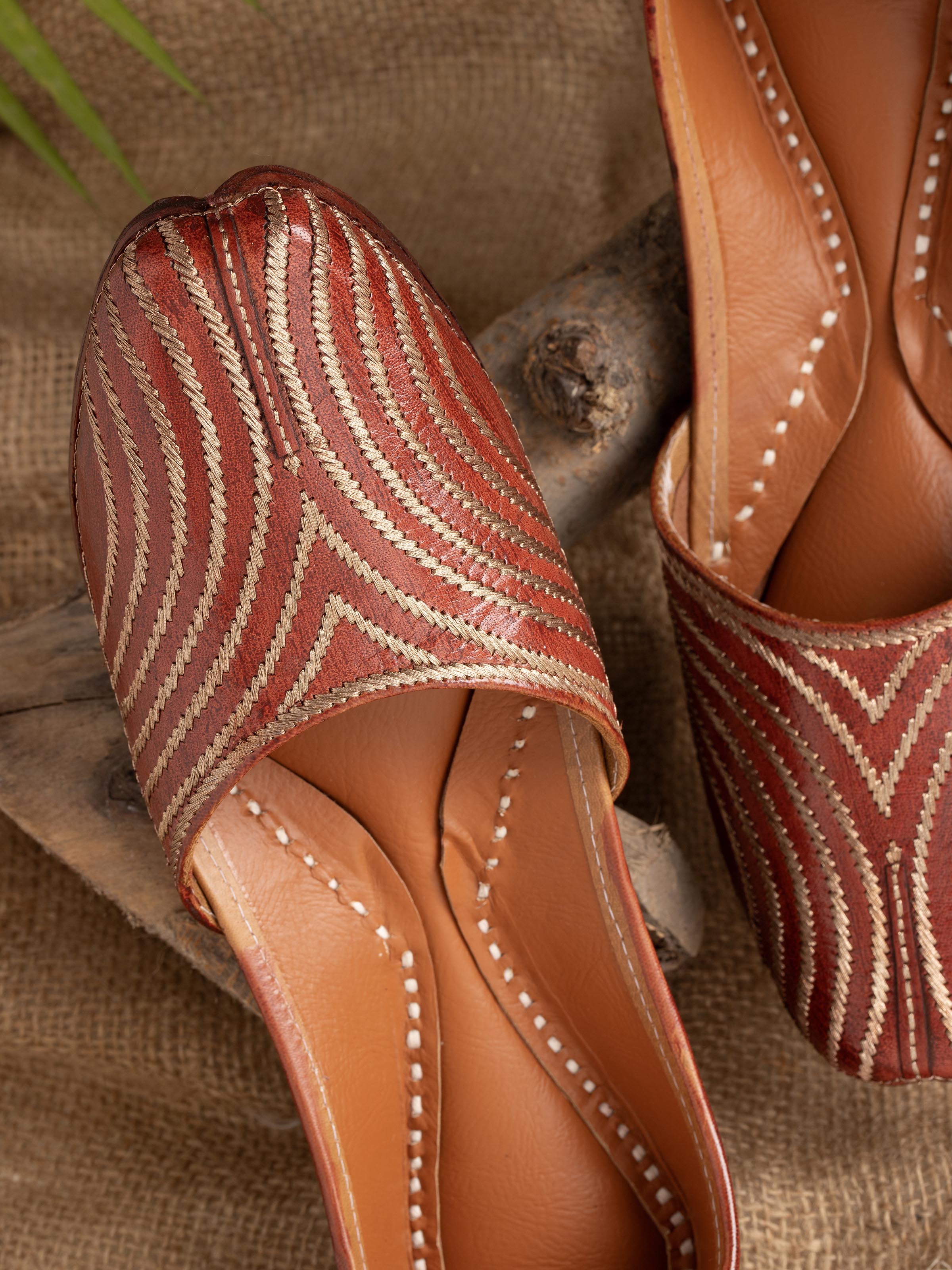 Close-up of brown leather embroidered punjabi juttis with focus on embroidery details