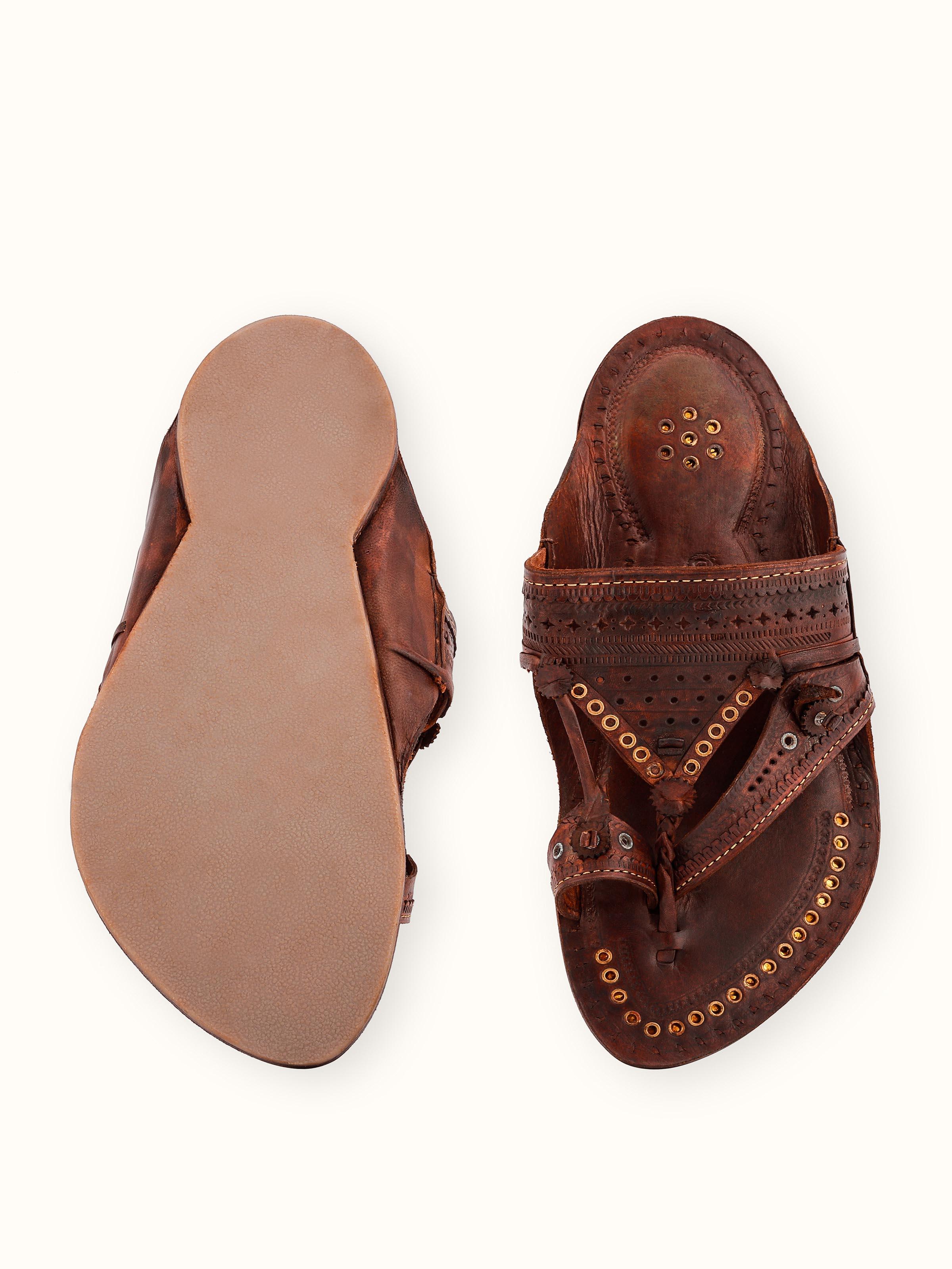 Detailed view of tan leather Kolhapuri chappals with focus on the traditional patterns