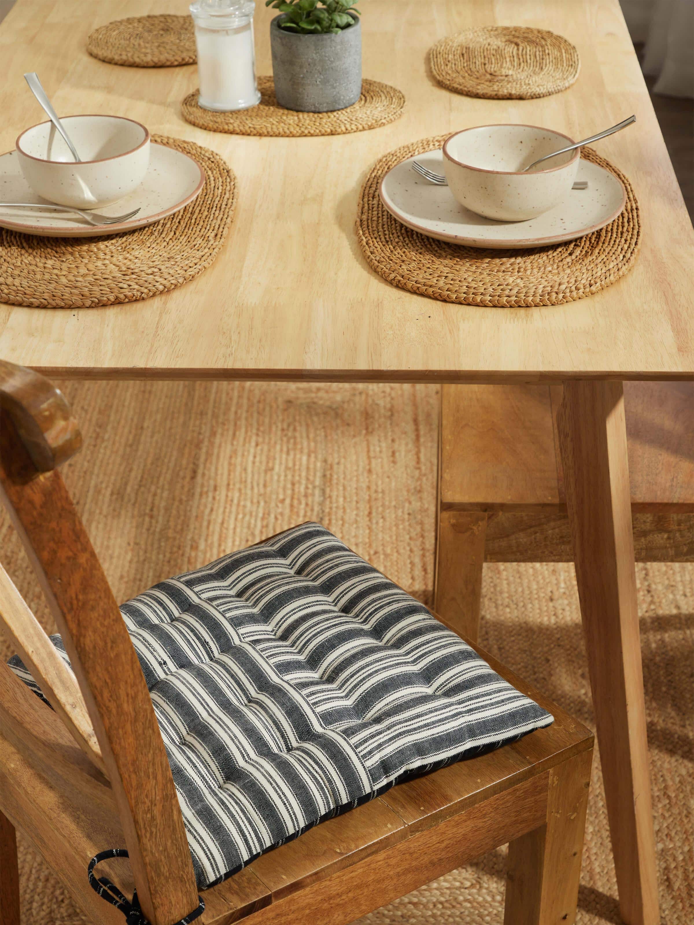 Lifestyle image showing Krsna handloom black cushion placed on a wooden chair – minimal decor