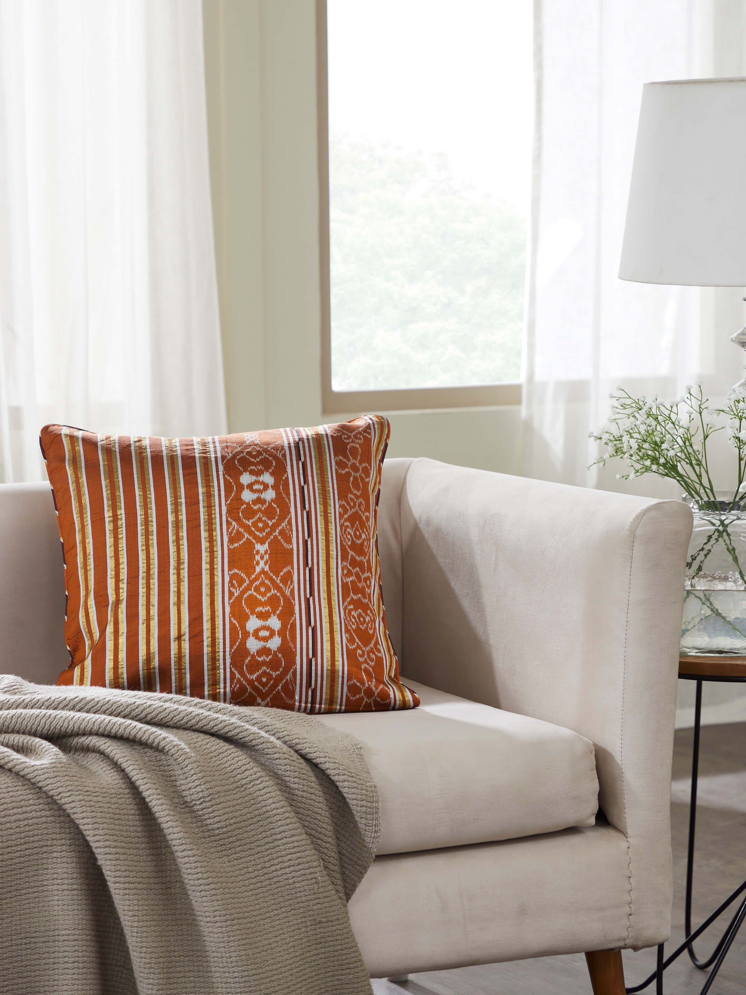 Side view of Sanchaya rust allover stripe silk Odisha ikat handloom cushion cover highlighting its texture and design.
