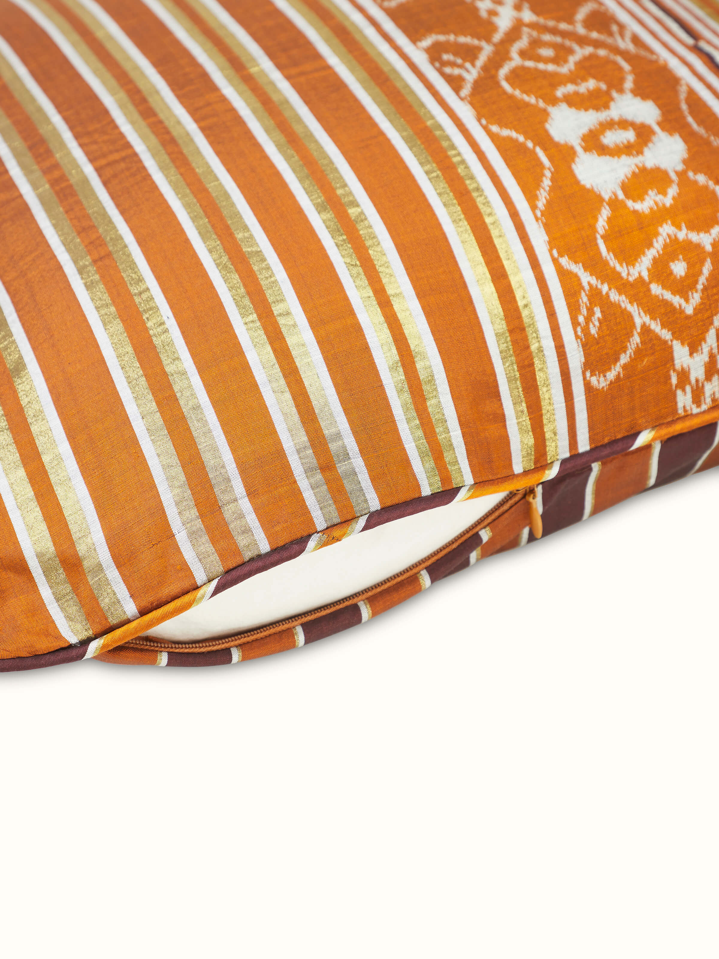 Angled view of Sanchaya rust allover stripe silk Odisha ikat handloom cushion cover showing the overall pattern and quality.