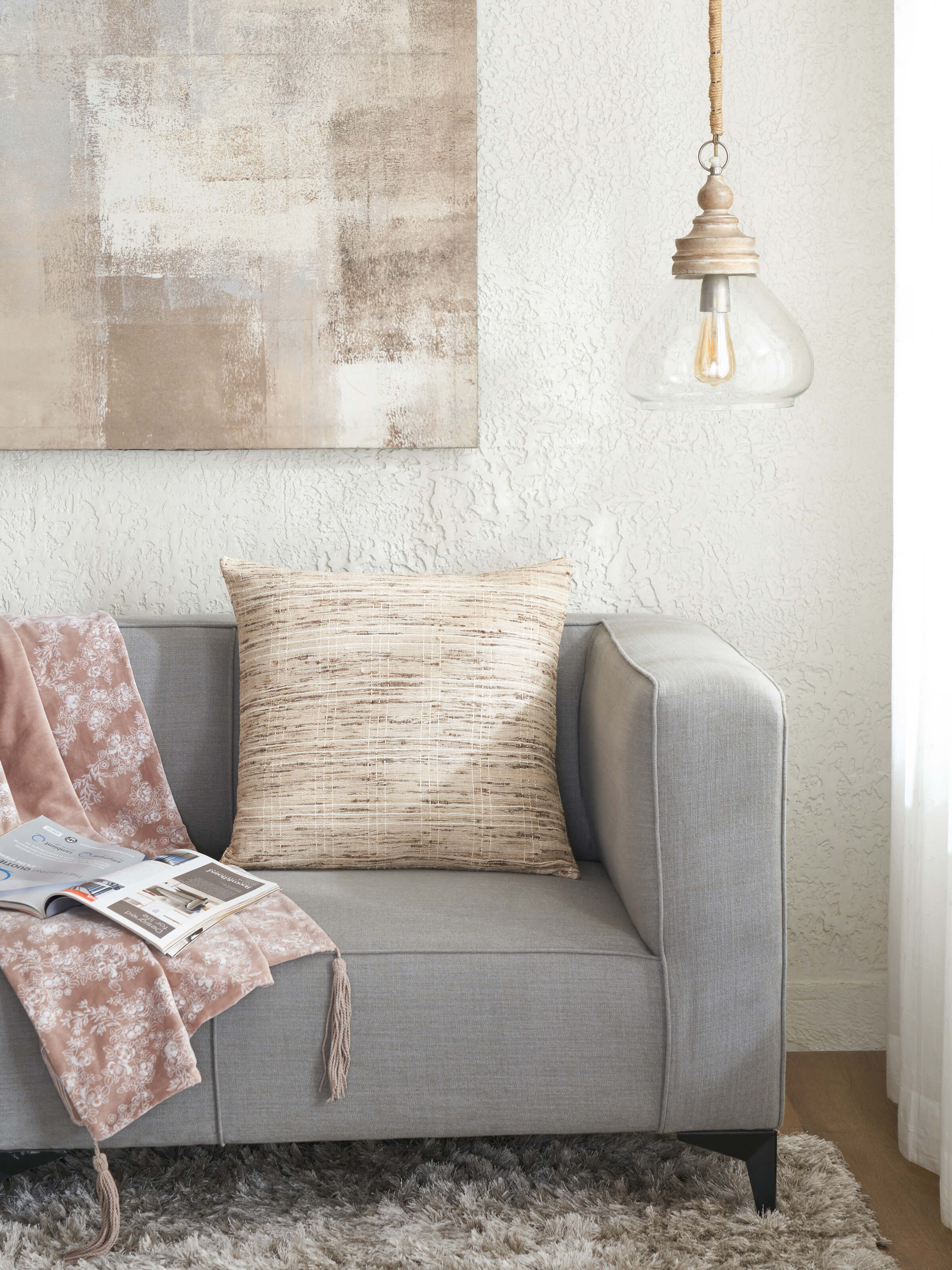 Lifestyle shot of silk cushion styled with soft-toned bedding and accent pillows.