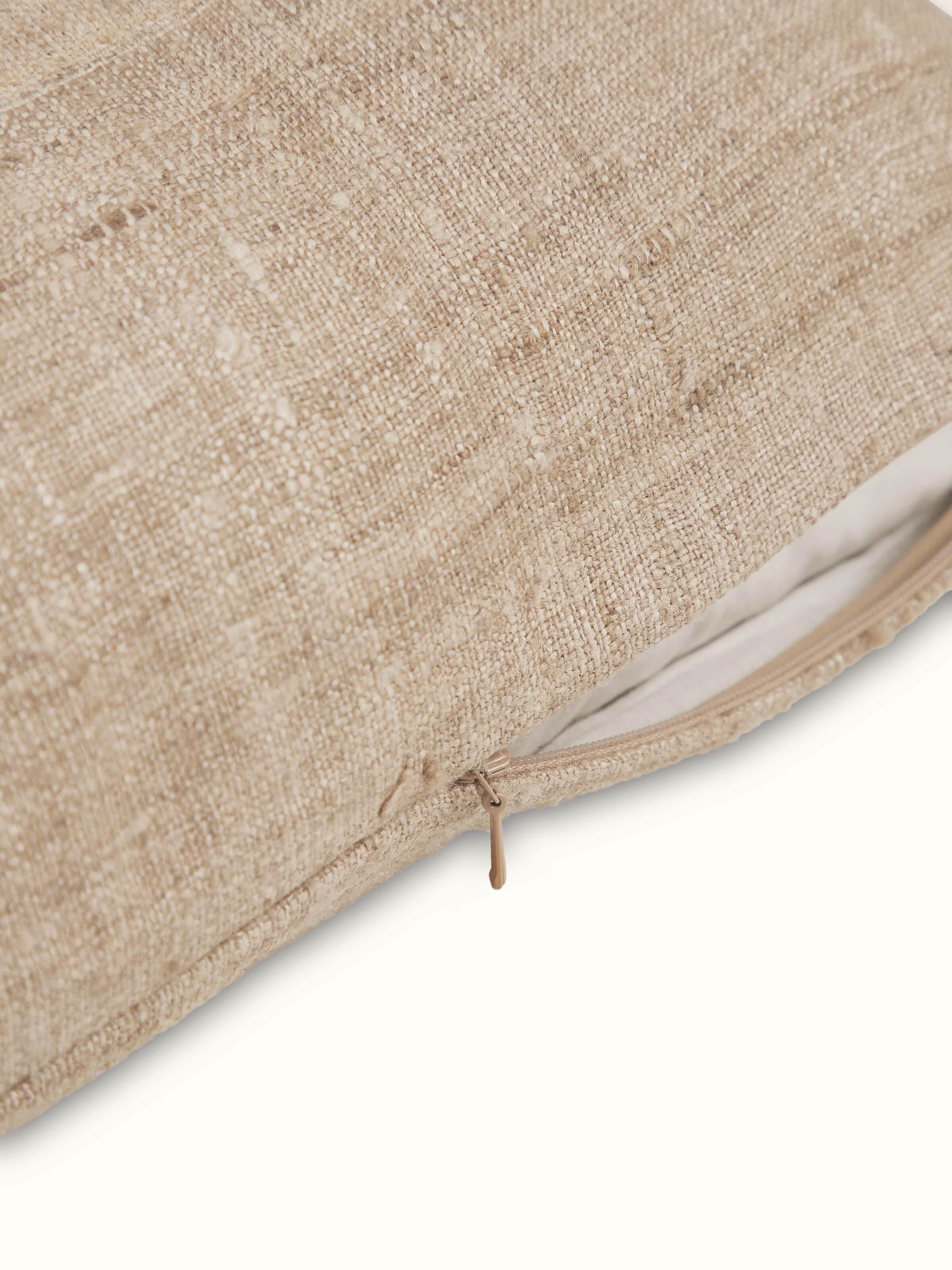 Angled view of Ujjal light brown dharana silk slub handloom cushion cover showing the fine details of the fabric and craftsmanship