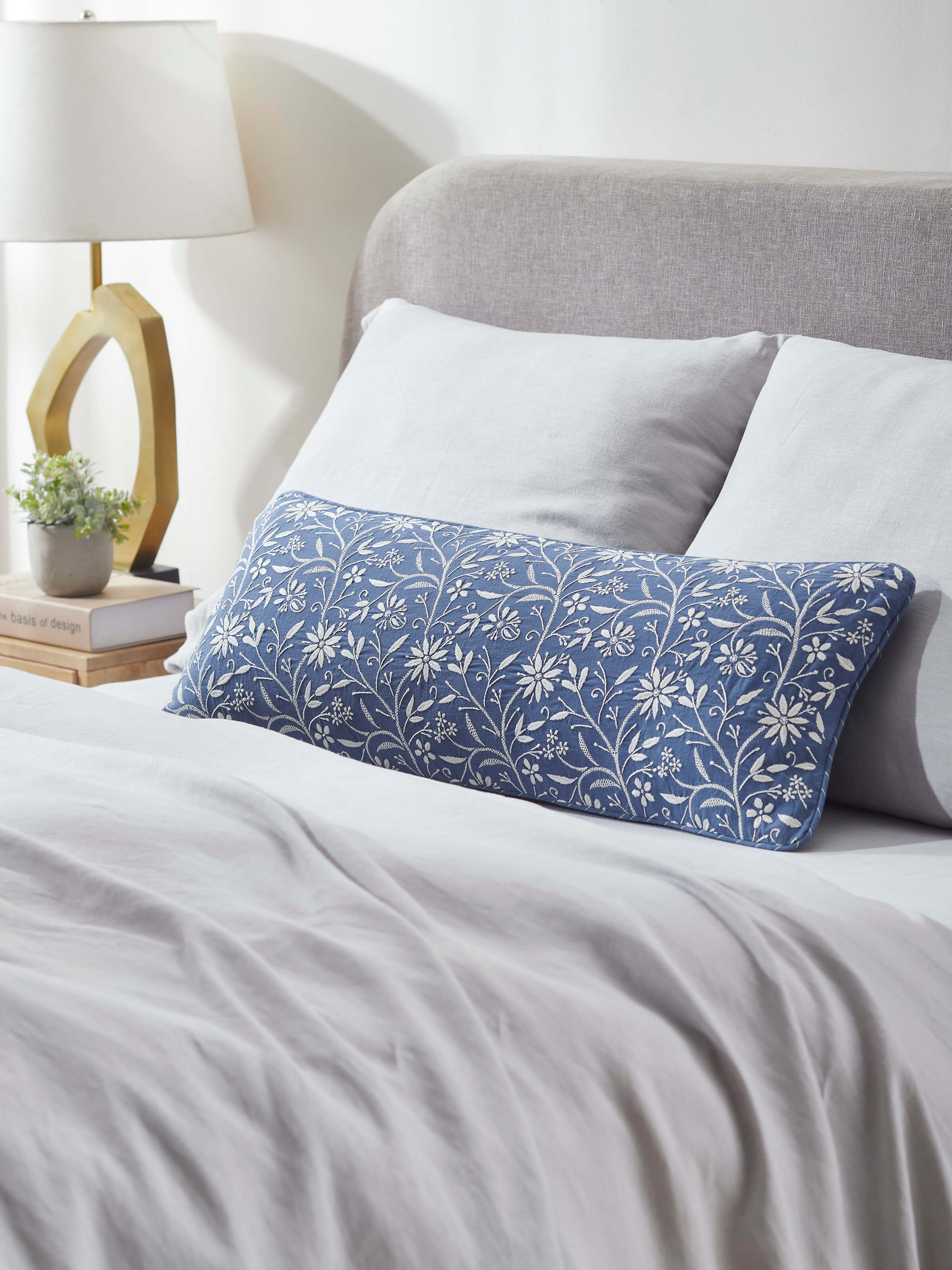 Lifestyle view of Rann hand-embroidered lumbar cushion cover placed on a sofa.