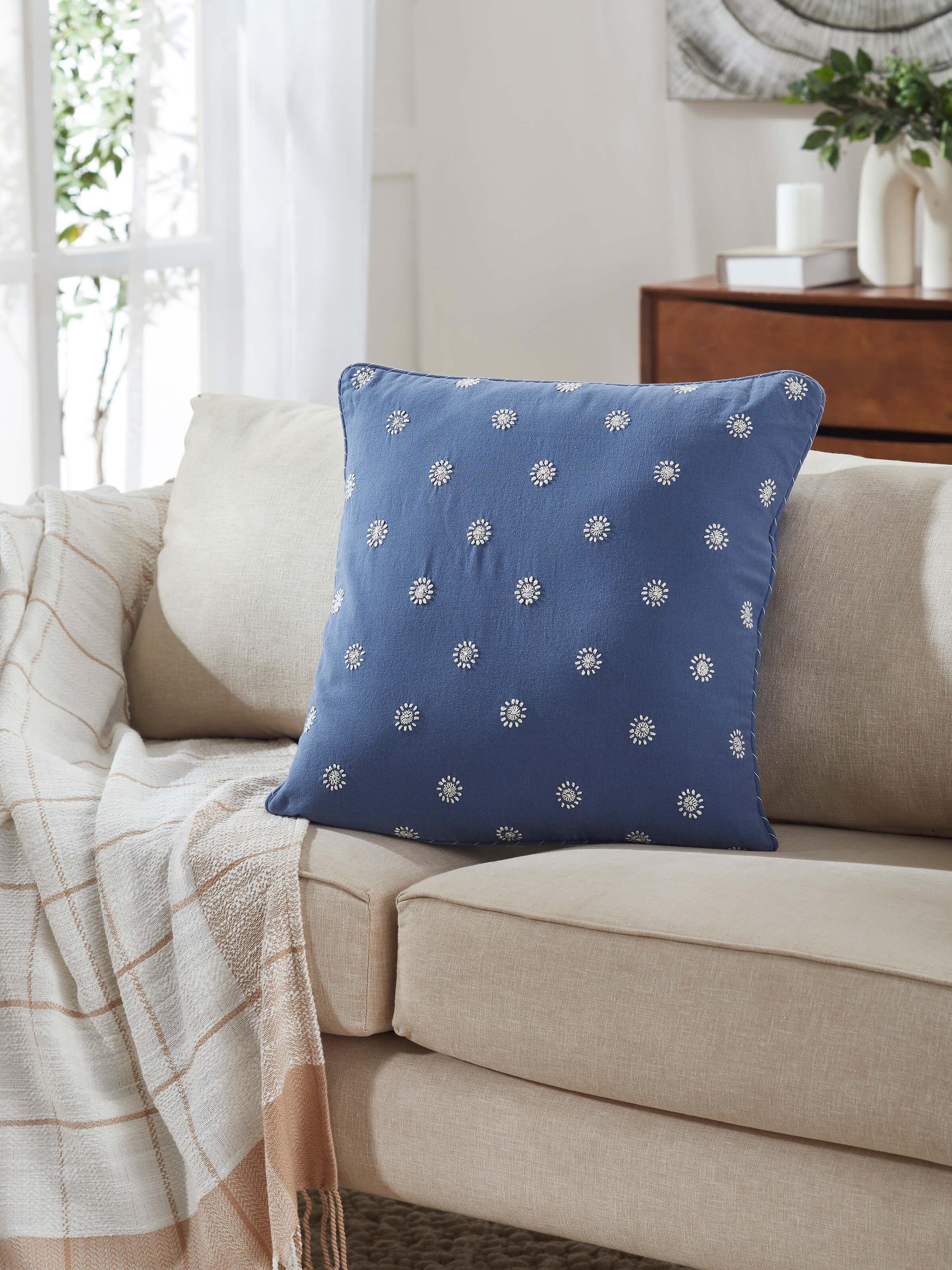 Lifestyle shot showing Rann blue hand embroidered Chikankari cushion cover on a white couch.