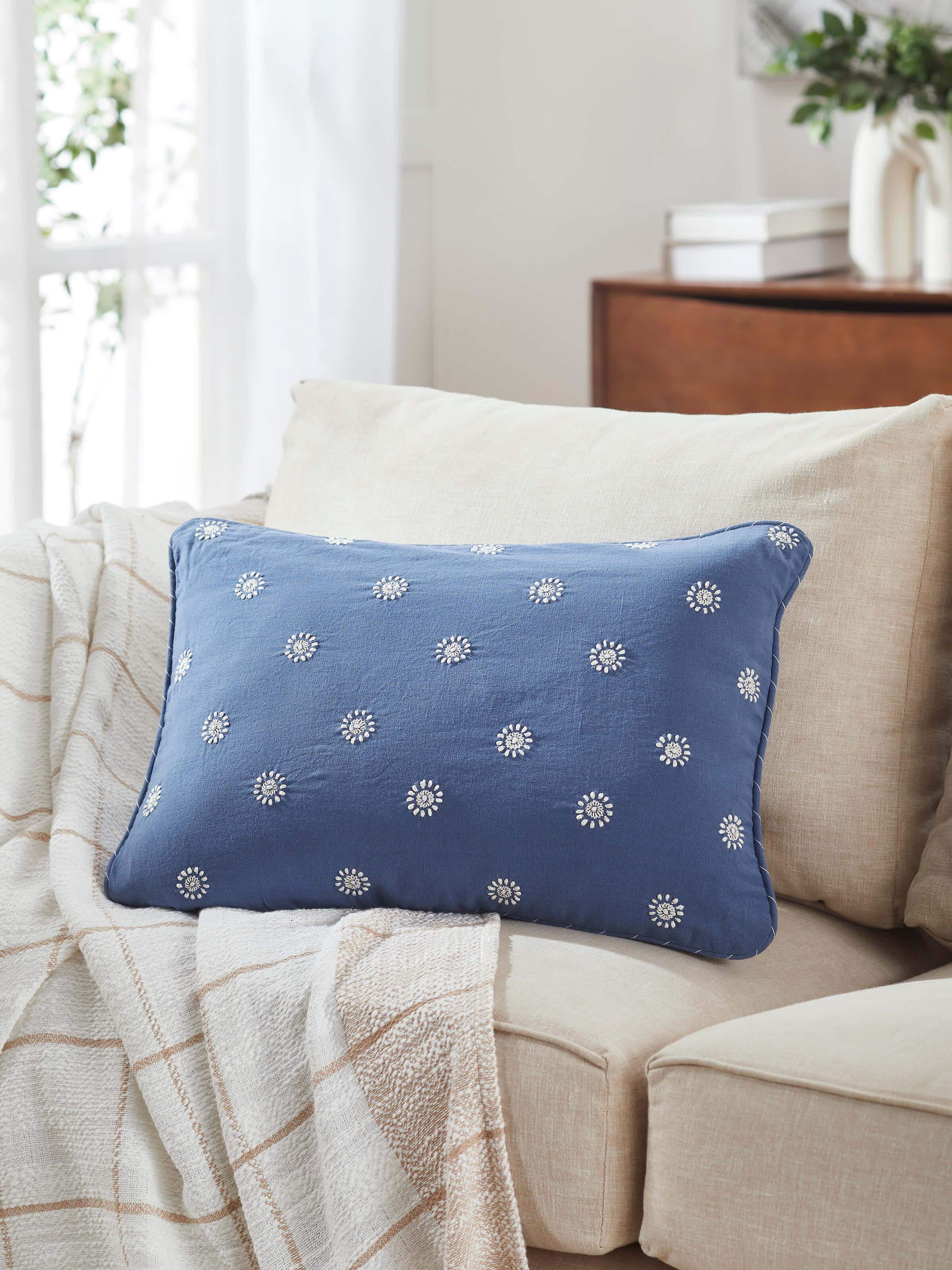 Lifestyle shot of blue Chikankari lumbar cushion placed in a styled seating area.