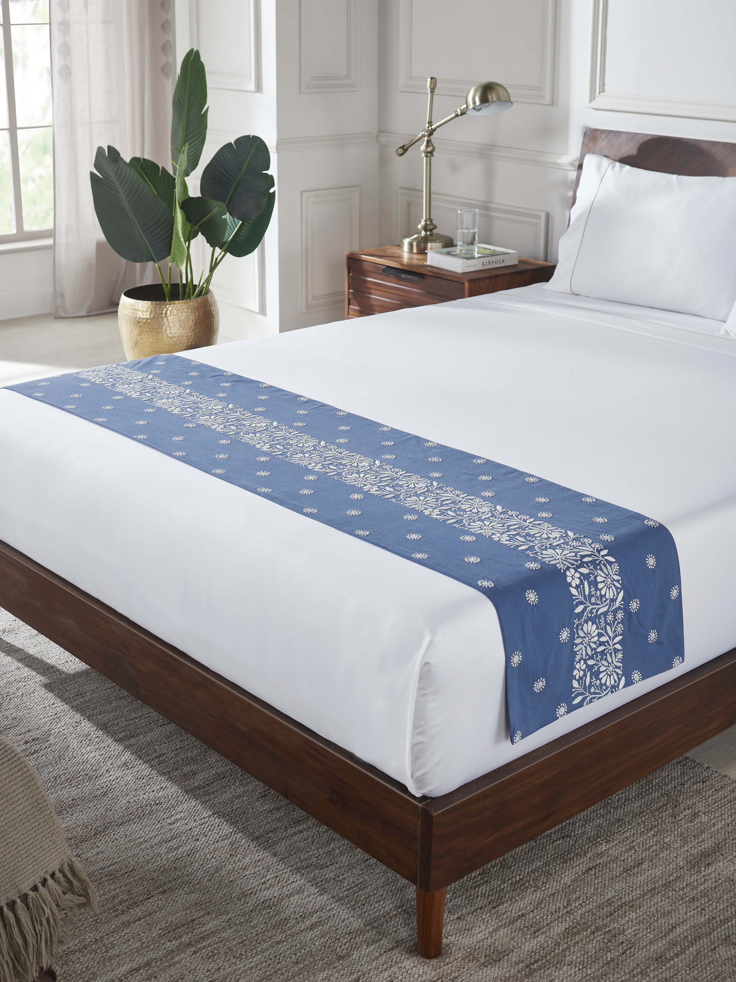 Lifestyle view of Rann hand-embroidered linen bed runner styled over a bed.