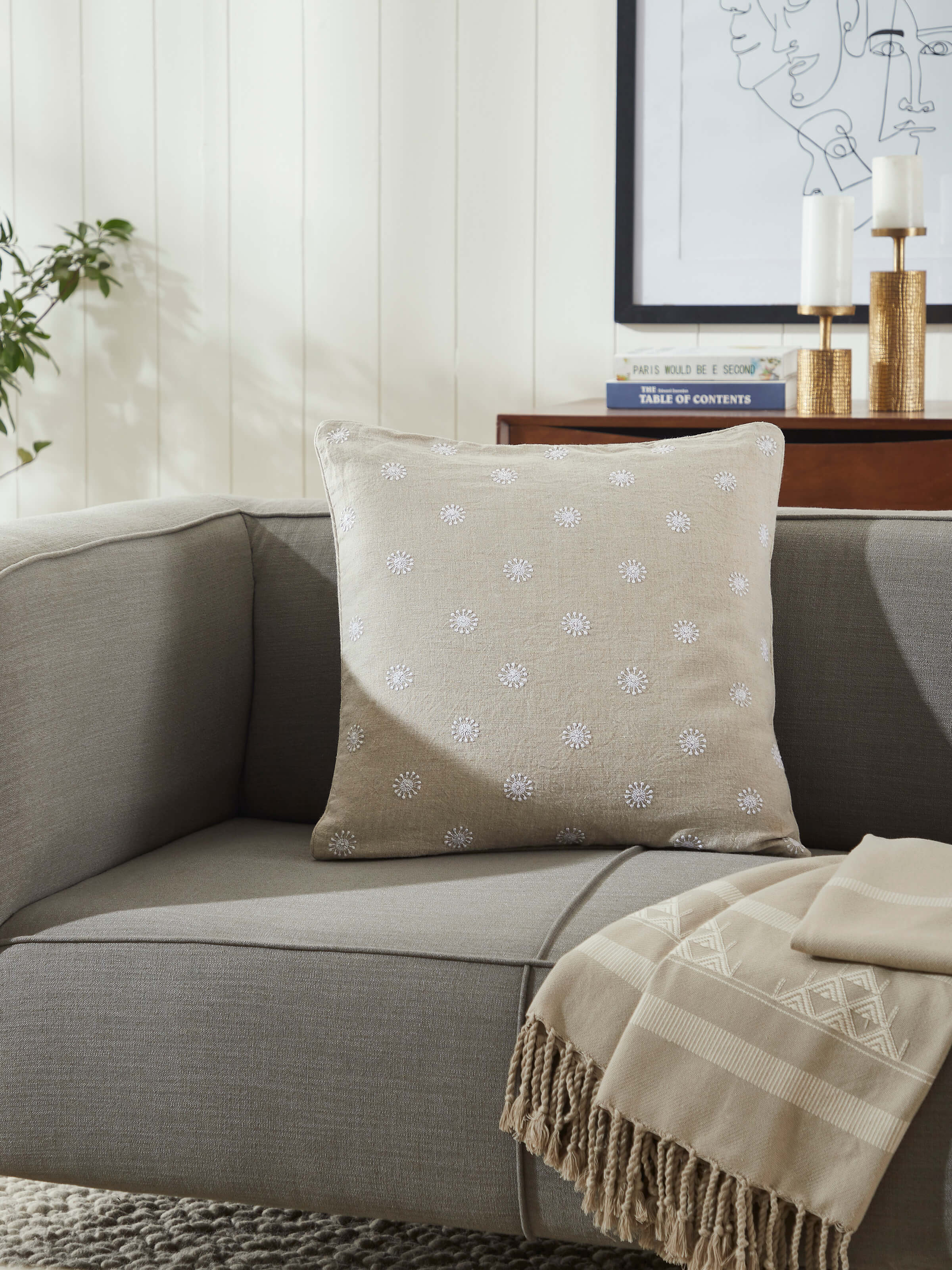 Lifestyle image showing Rann beige embroidered cushion on a sofa – soft and artisanal look