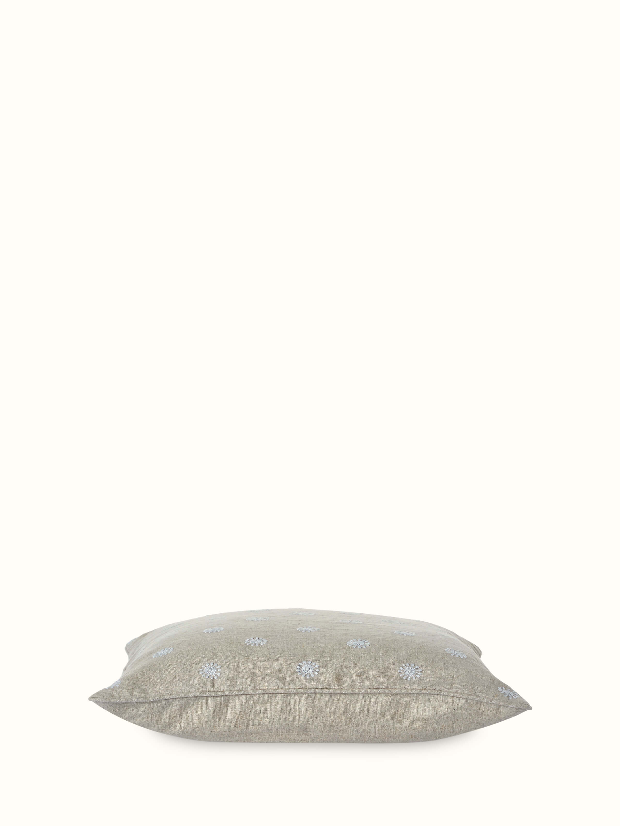 Angled view of Rann cotton cushion cover displaying intricate floral Chikankari work