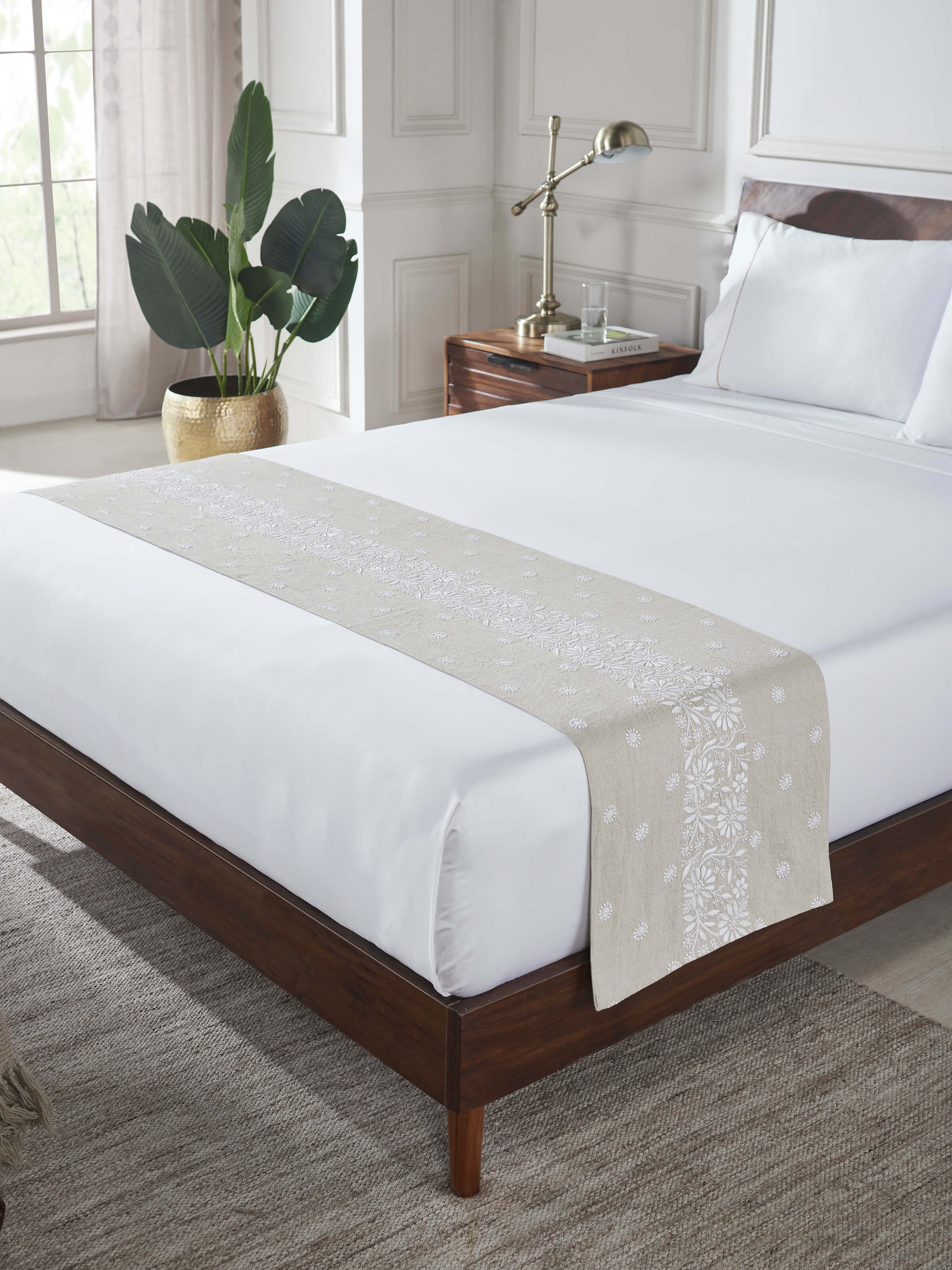 Lifestyle image of embroidered linen bed runner, styled over neutral bedding for a refined accent.