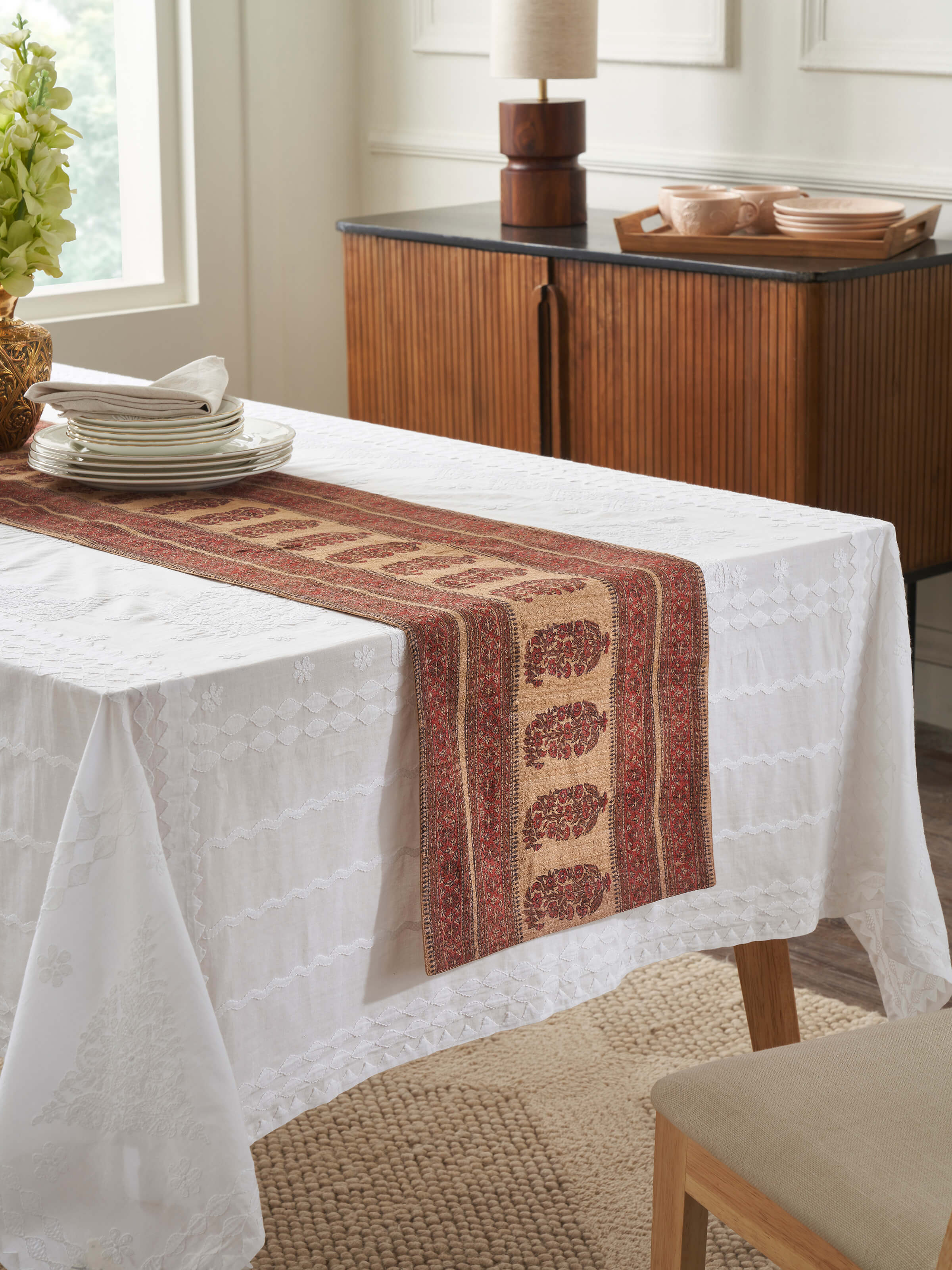 Lifestyle shot featuring Vasudha rust table runner on a wooden dining table – elegant ethnic look