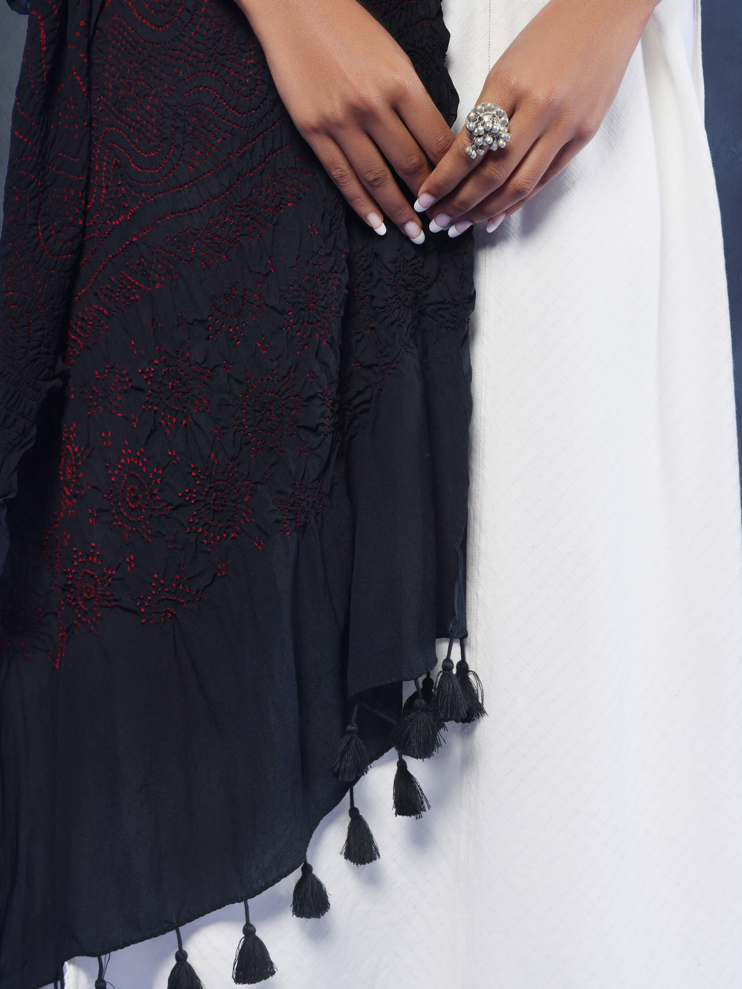 Close-up view of red Bandhani dupatta highlighting white tie & dye motifs on silk fabric.