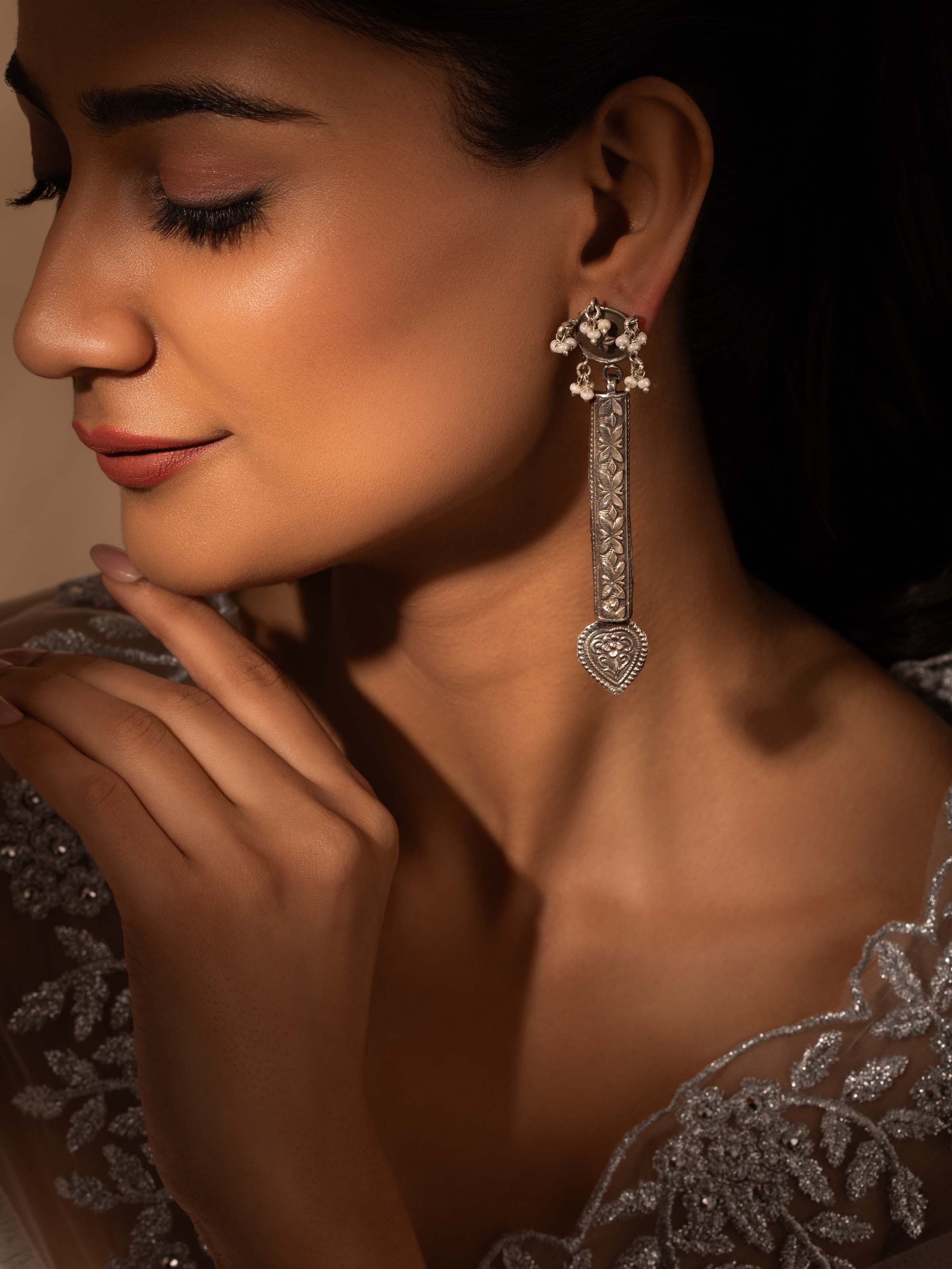 Close-up view of silver smithing drop earrings highlighting intricate craftsmanship.