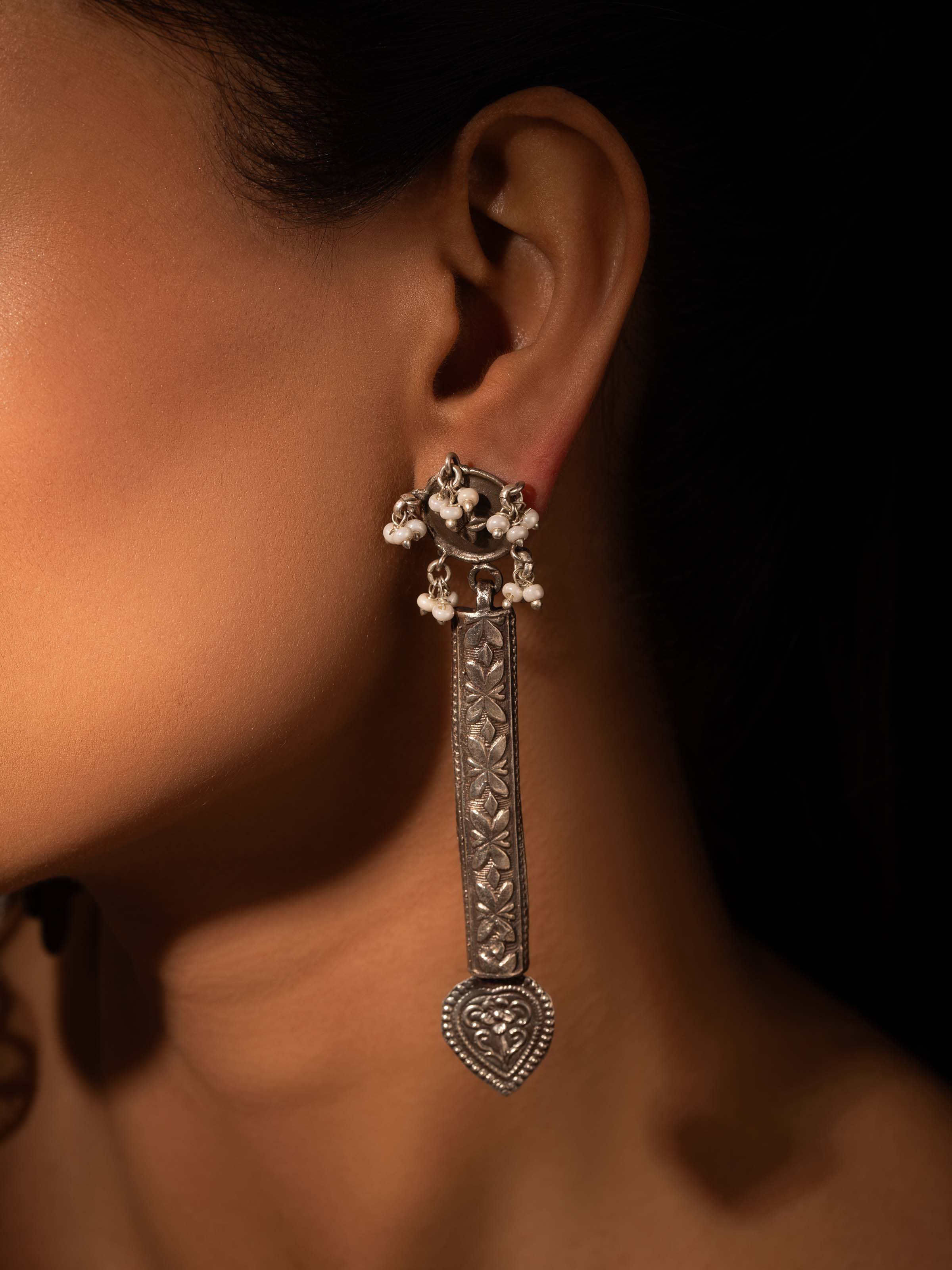 Side view of silver smithing drop earrings emphasizing design and elegance.