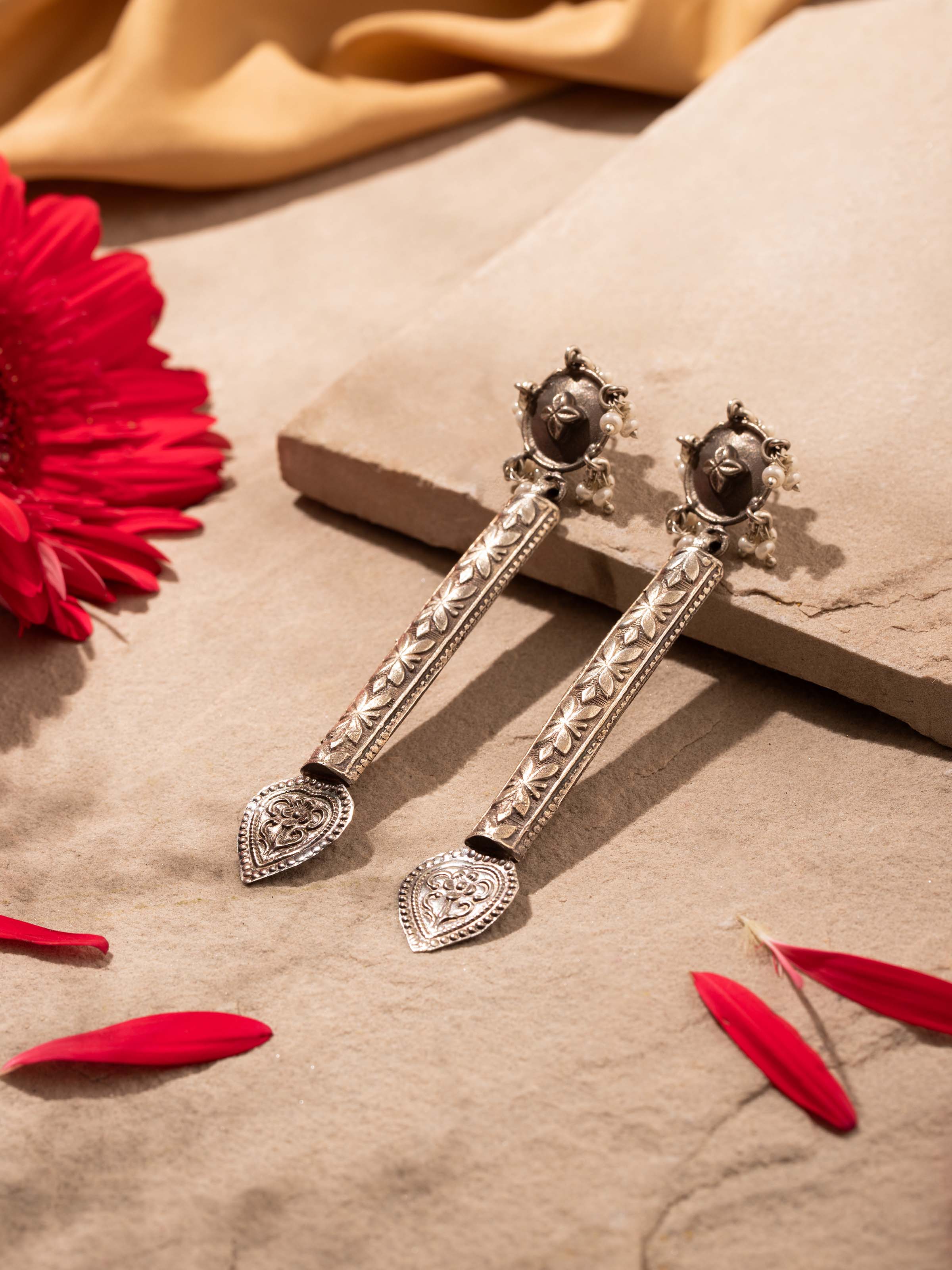 Angled view of silver smithing drop earrings showcasing detailed design and finish.