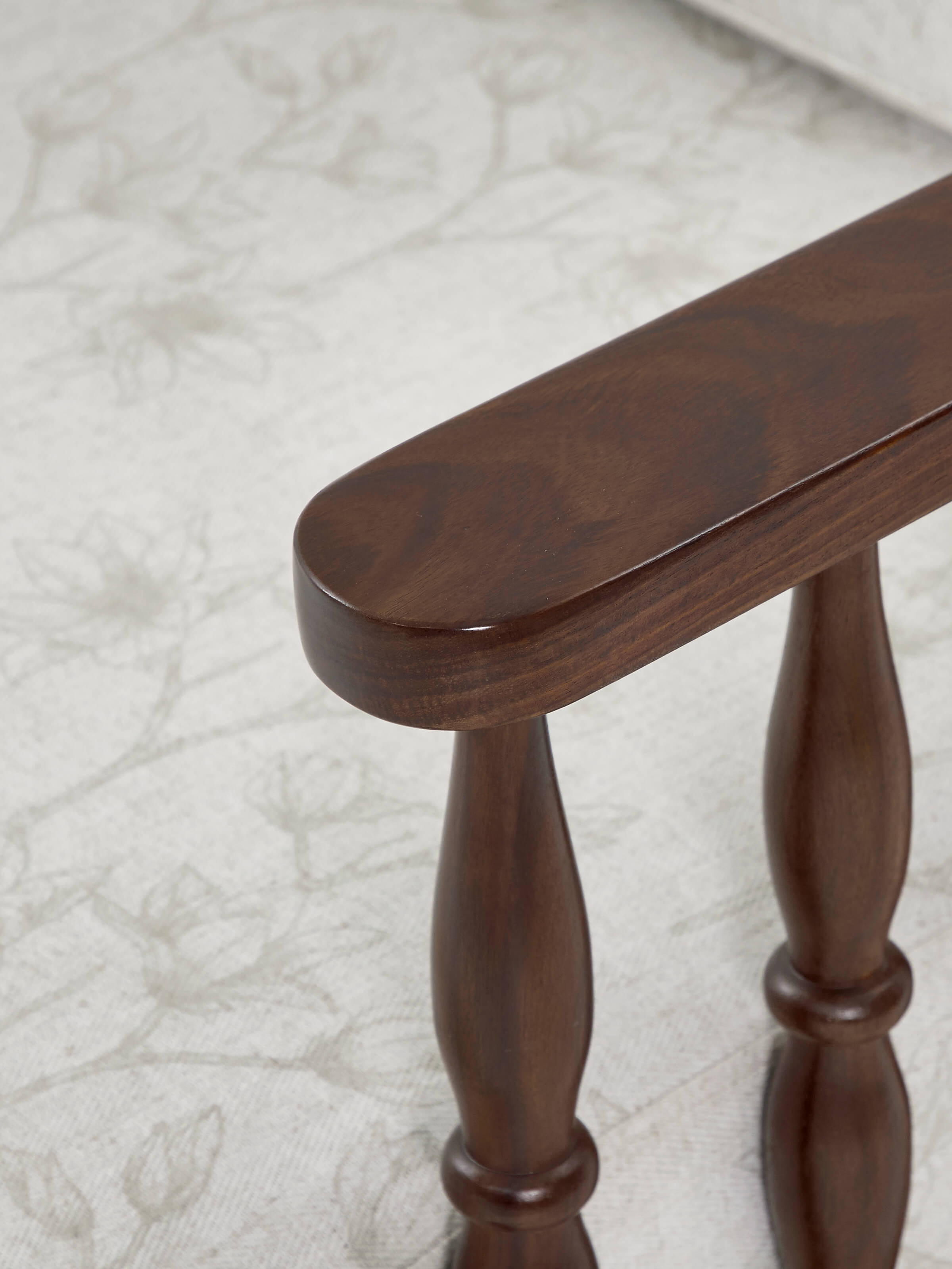 Back view of the teak finish upholstered sheesham wood 1-seater sofa, showcasing its smooth wood finish and sturdy construction.