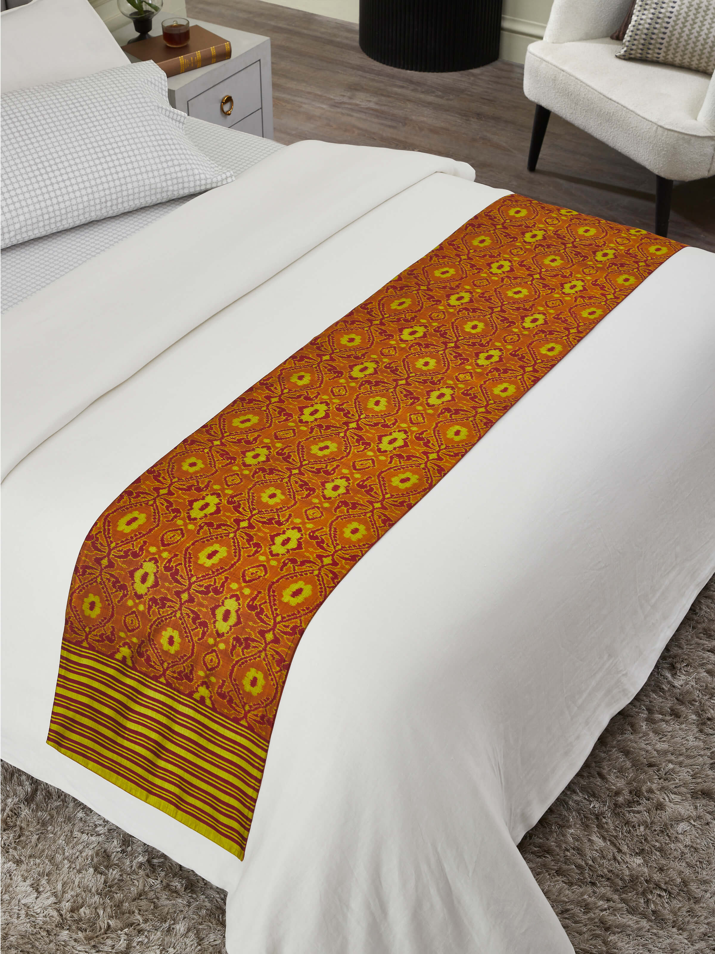 Lifestyle view of Bhoomi red Ikat handloom bed runner elegantly layered on a neutral bedding set