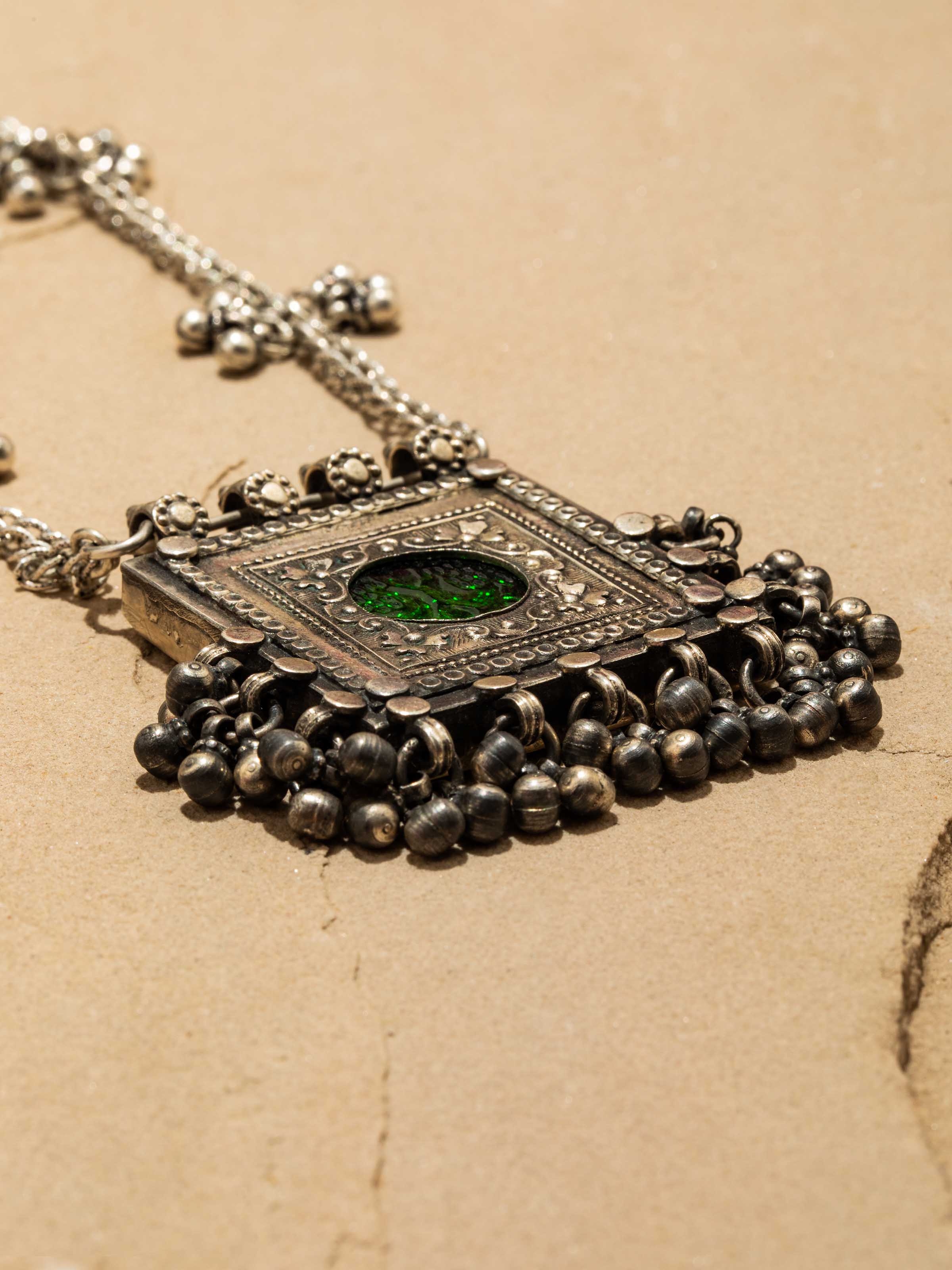 Side view of elegant silver long necklace with a detailed pendant featuring traditional craftsmanship.