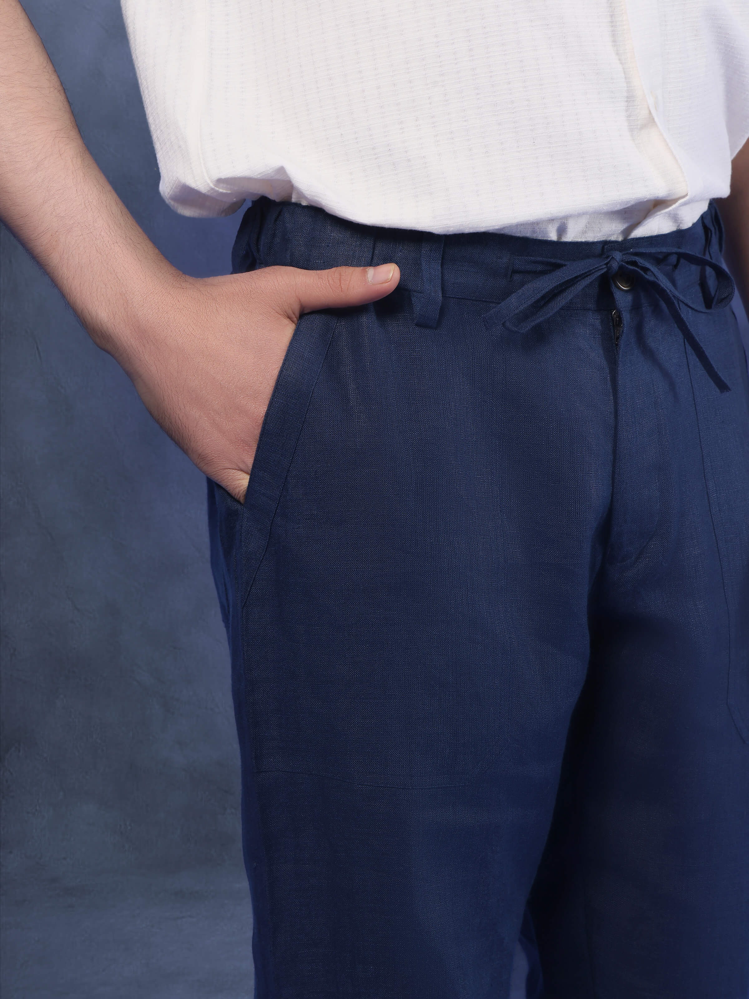 Angled view of navy blue linen elasticated pant highlighting waistband, pleats, and fall of the fabric.