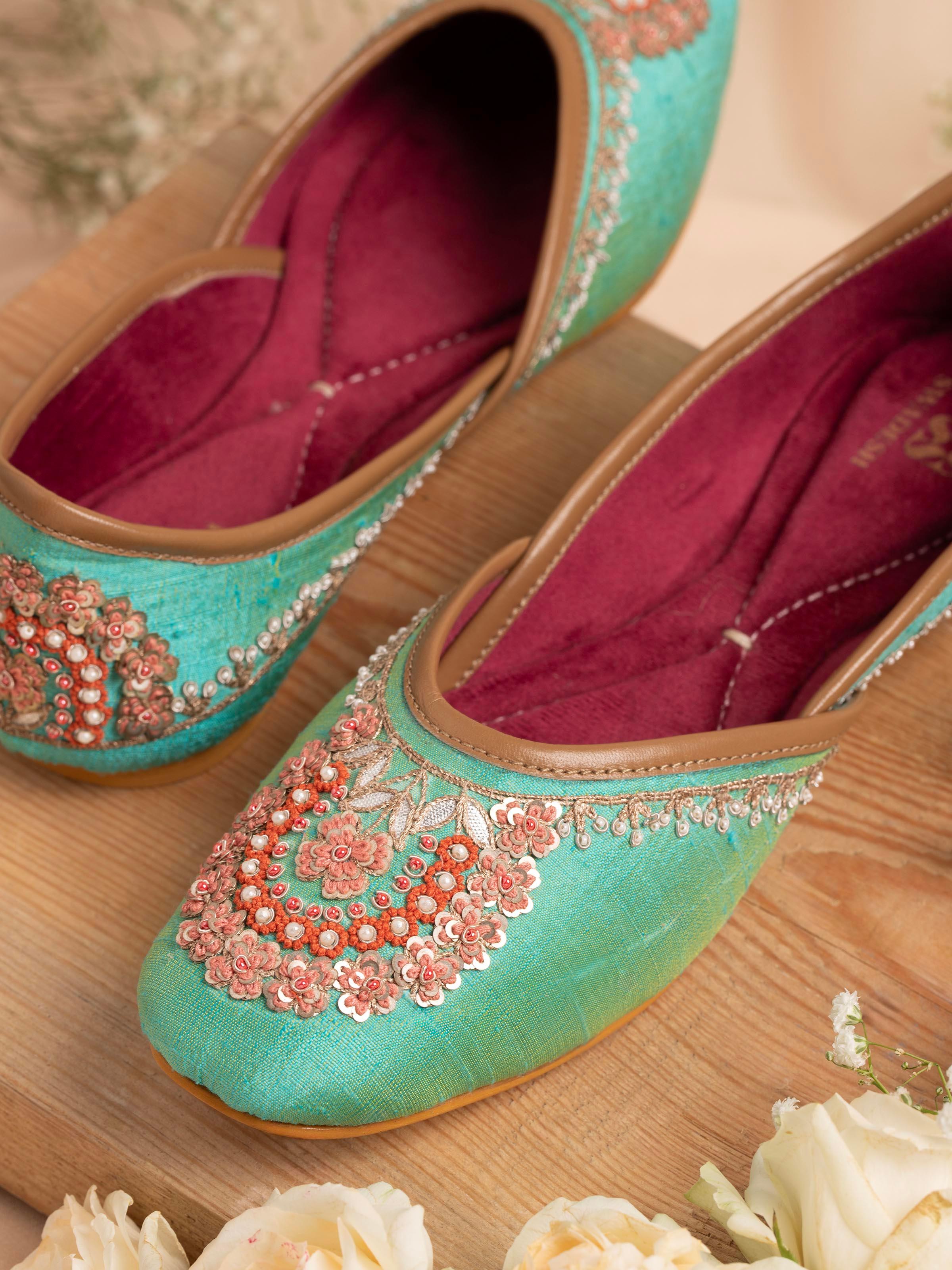 Side view of turquoise leather zardozi juttis highlighting the vibrant color and ornate embroidery