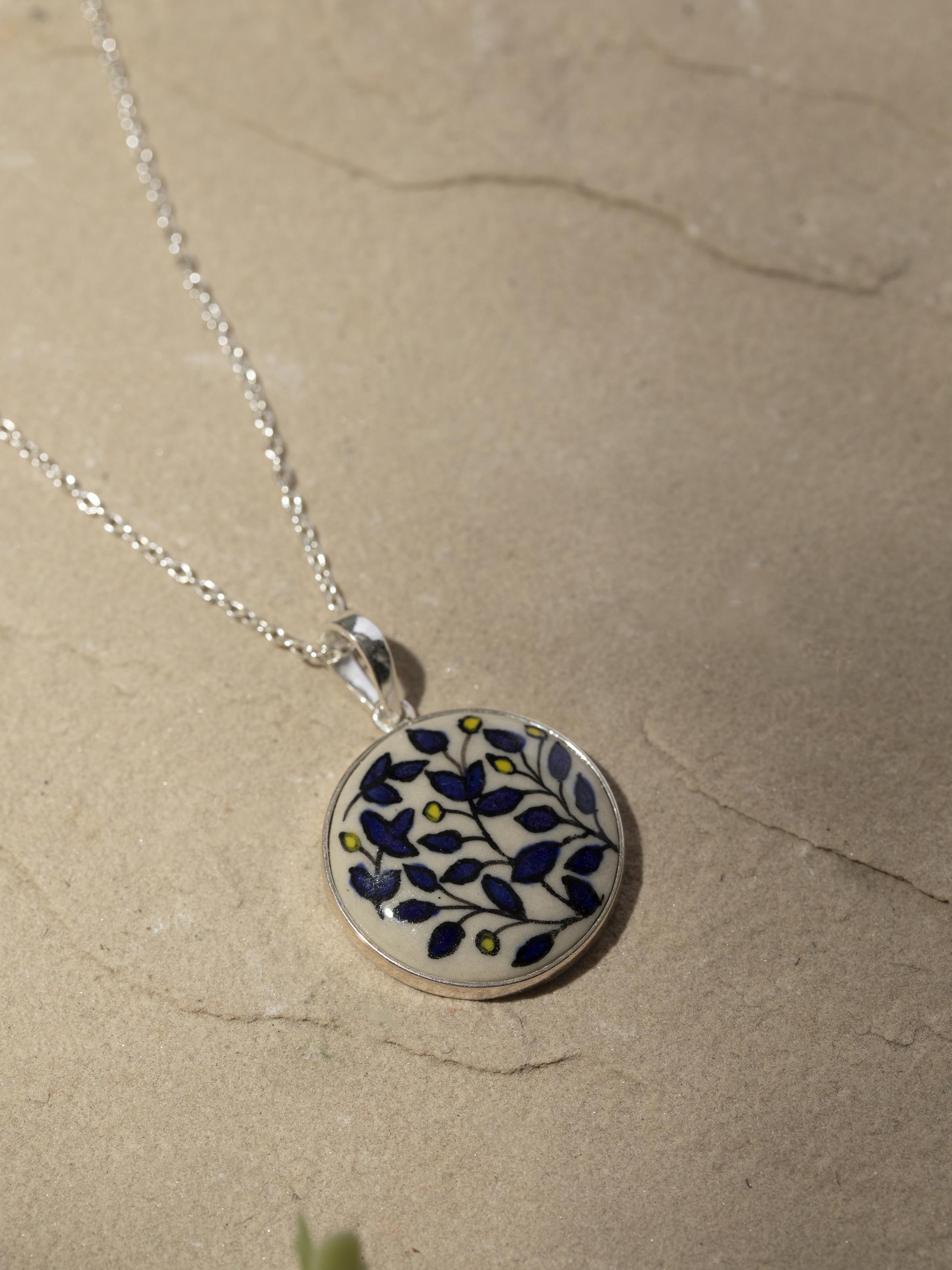 Detailed shot of ceramic pendant & chain focusing on its artistic ceramic work