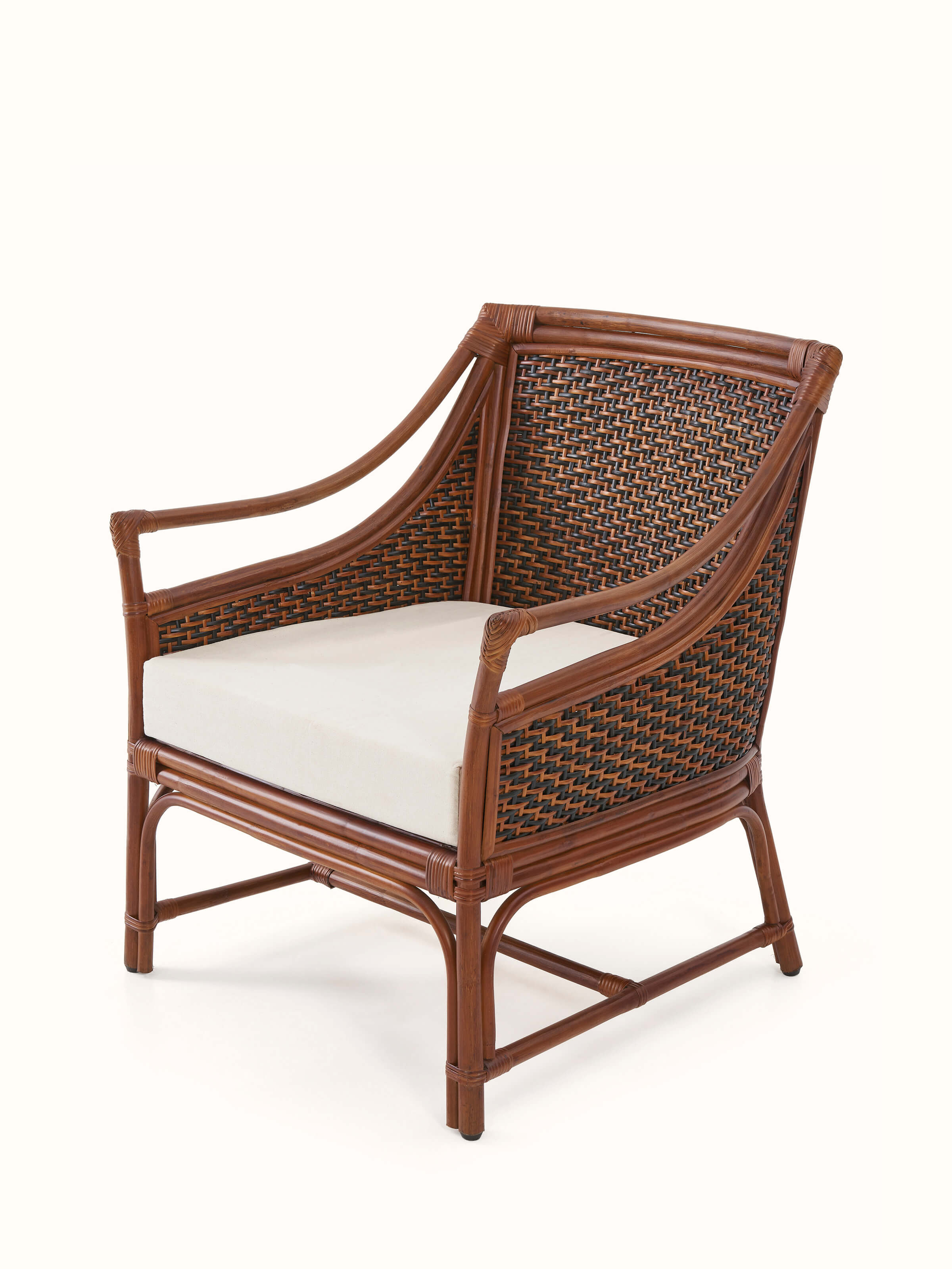 Angled view of the upholstered cane and cotton armchair, showing the integration of cane detailing and cotton upholstery.
