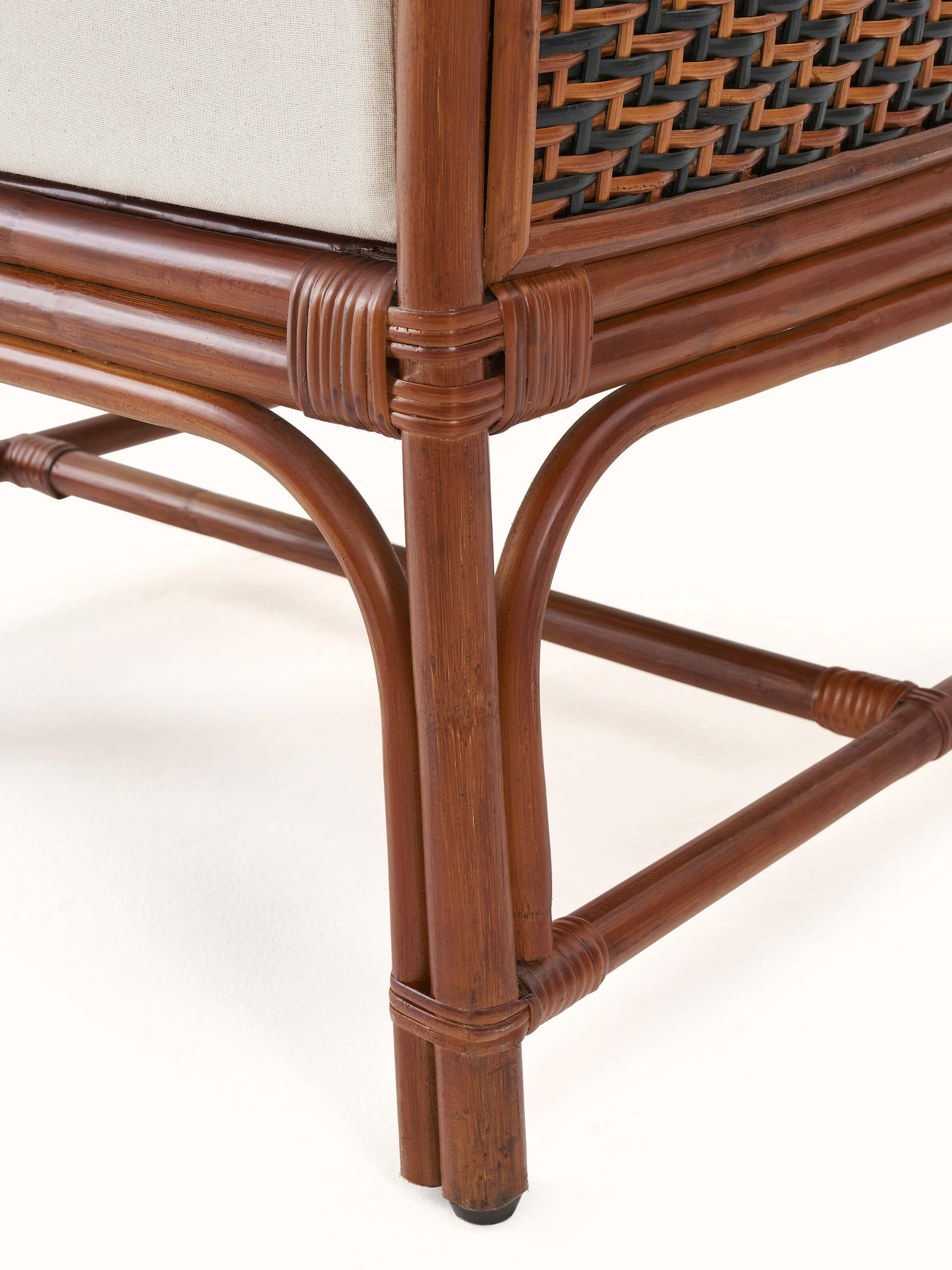 Rear view of the upholstered cane and cotton armchair, highlighting the cane backrest and overall design.