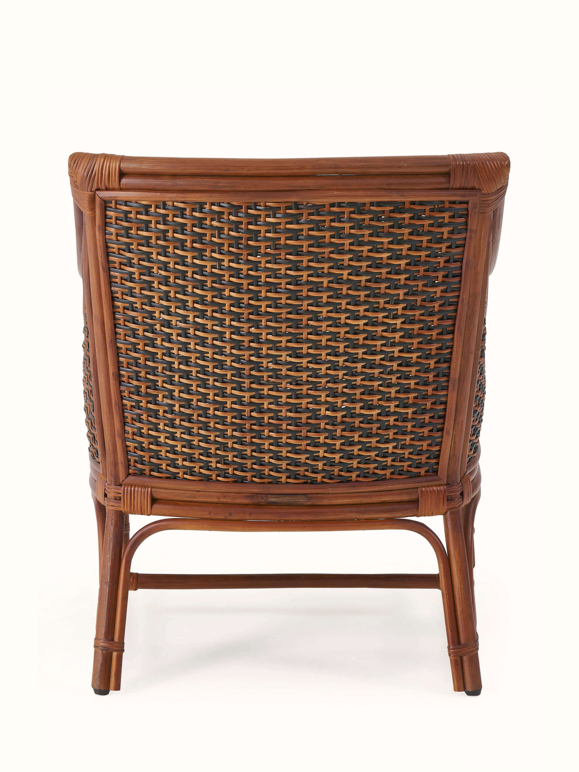 Angled view focusing on the overall style of the upholstered cane and cotton armchair, including the armrests and seat.