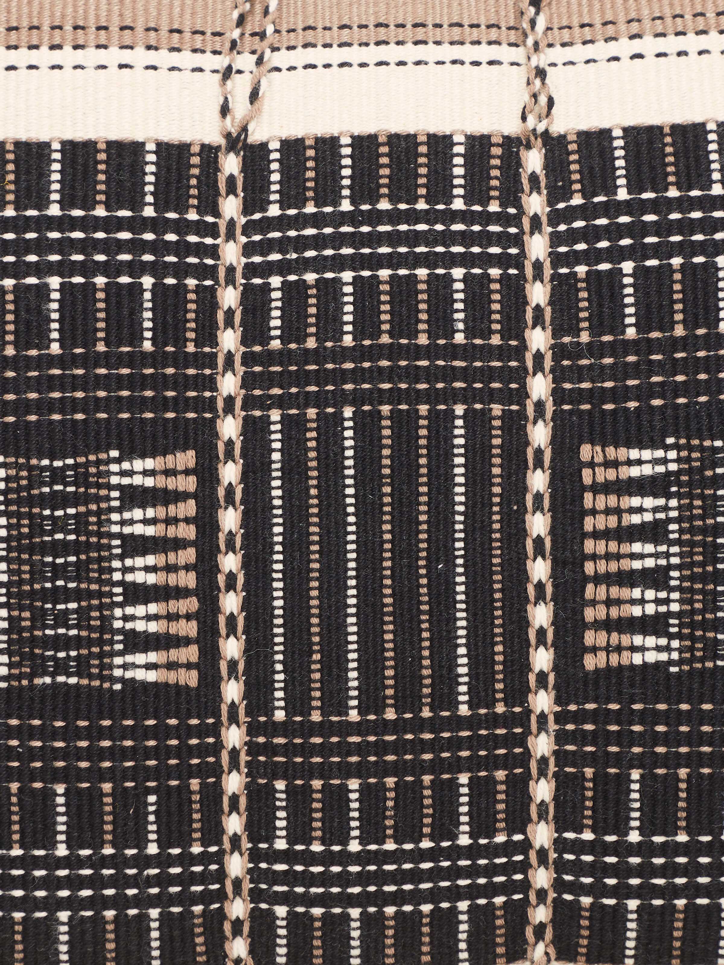 Angled view of Ridhama Black Mrunal Cotton Naga Handloom Cushion Cover, highlighting the cushion's edges and design.