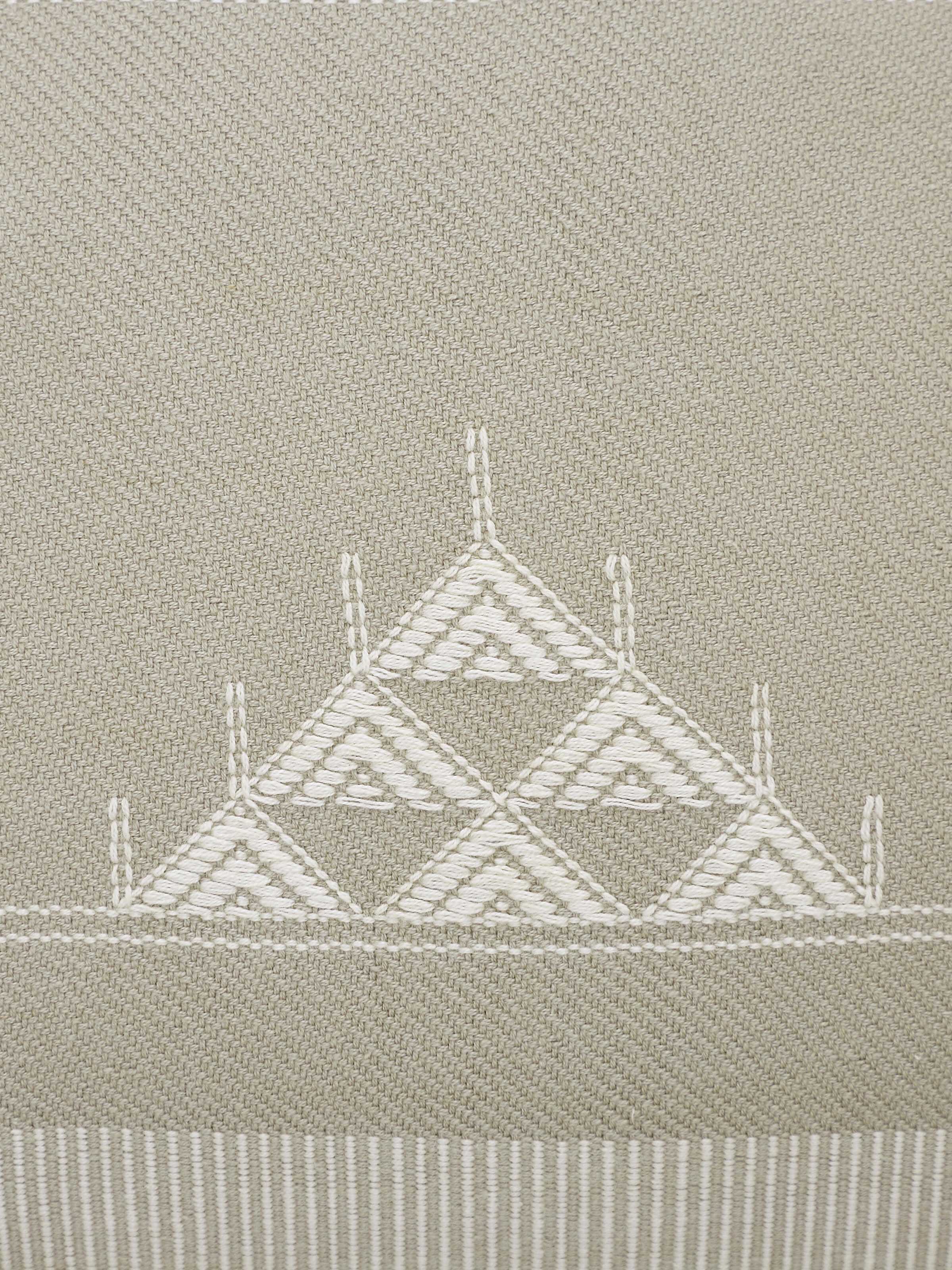 Artistic view of Godna light beige triangular stripe cotton handwoven pattu cushion cover in a room setting