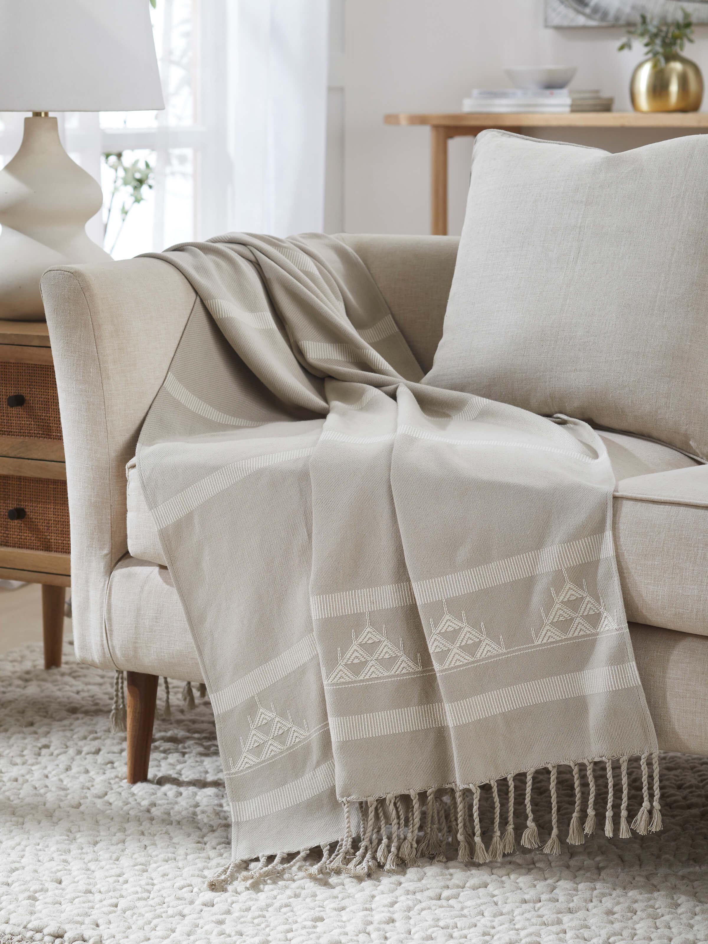 Throw styled on a chair showing Godna beige cotton texture and woven stripe pattern.