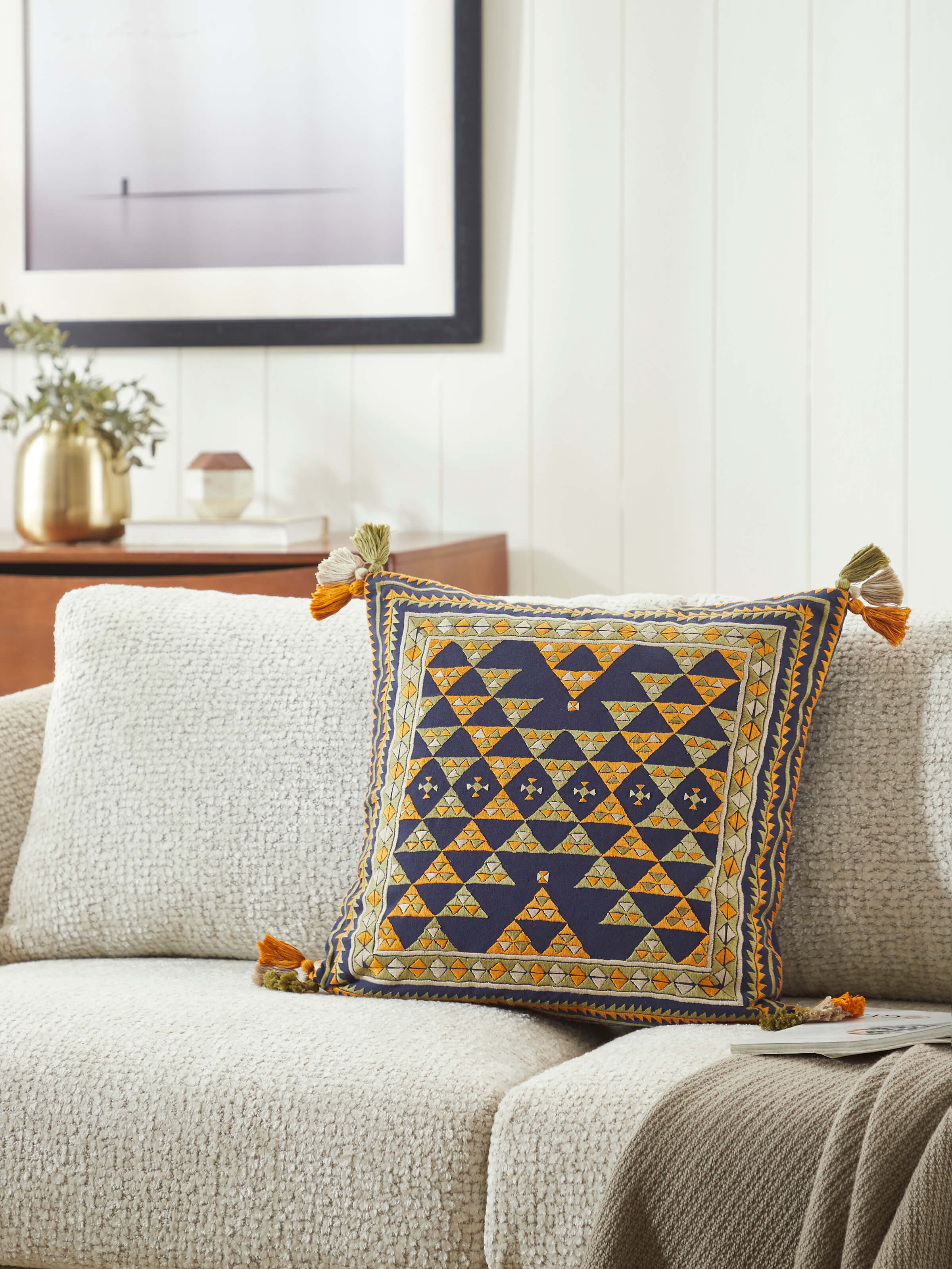 Lifestyle view of Suf embroidered cushion cover styled on a wooden seat with blue decor
