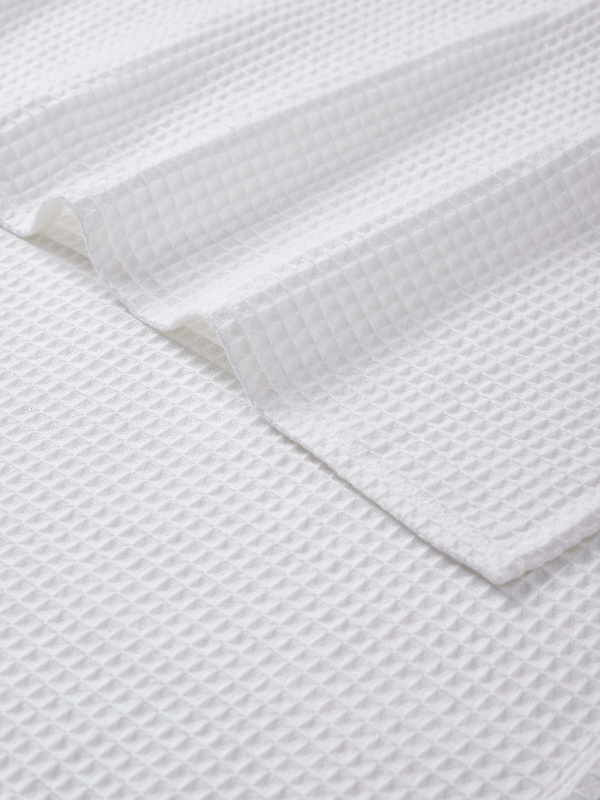 Angled view of Amala waffle white solid cotton bath towel displaying its edge and texture
