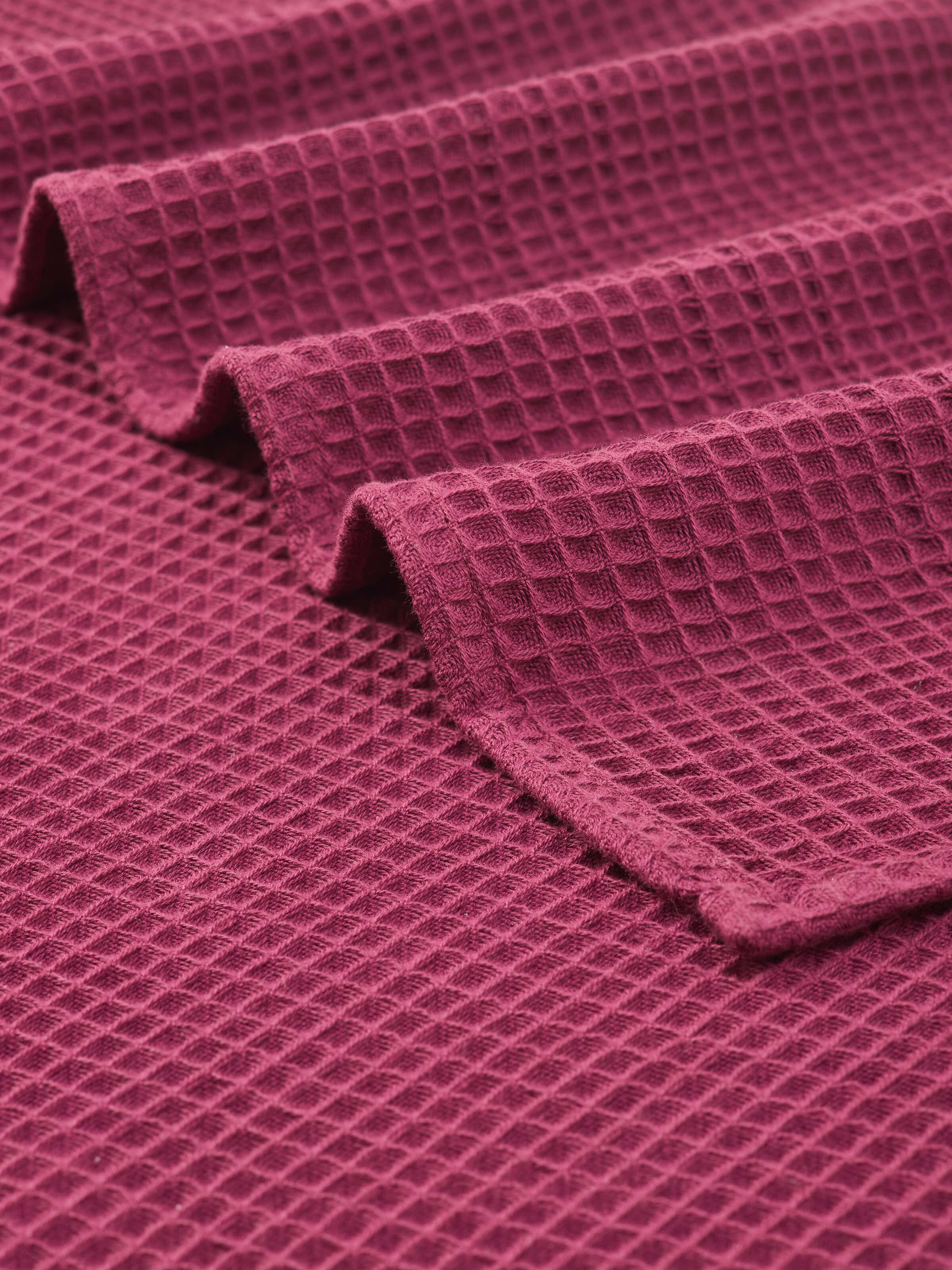 Angled view of Amala Waffle Purple Solid Cotton Bath Towel (M), showing the towel's full design and texture.