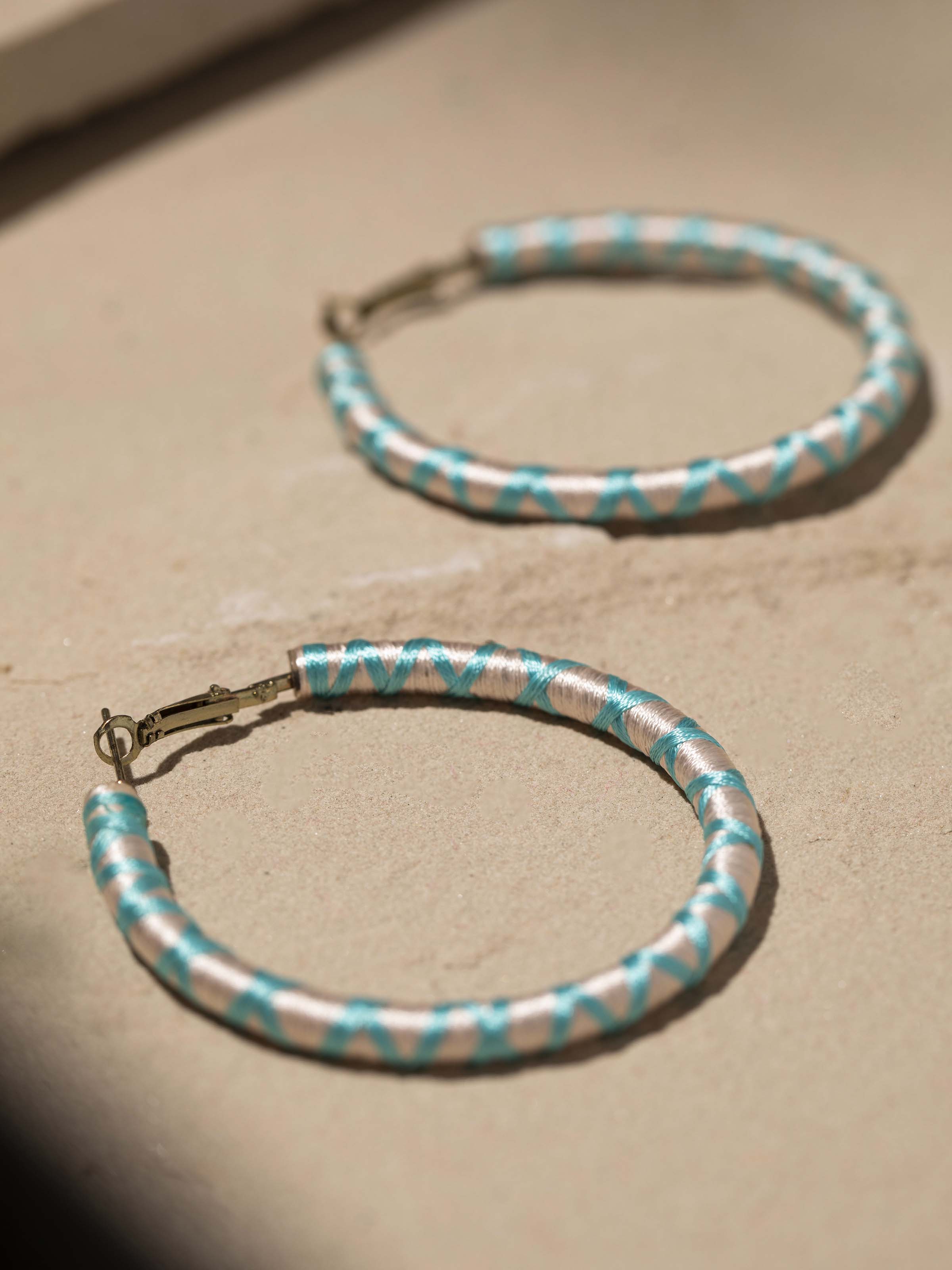 Detailed close-up of handcrafted hoop earrings focusing on the fine details and craftsmanship.