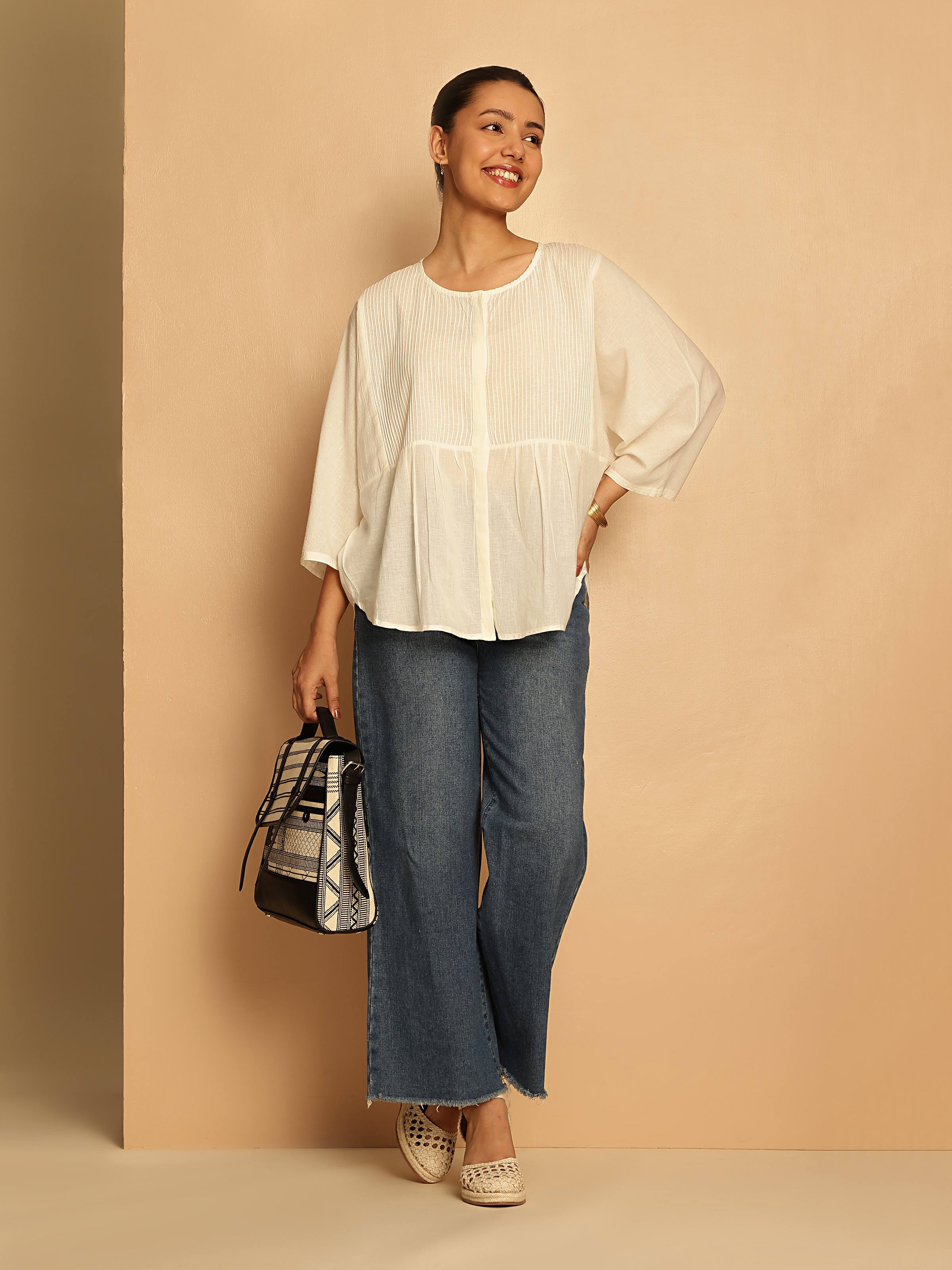 Side view of white cotton hand-spun top with relaxed silhouette