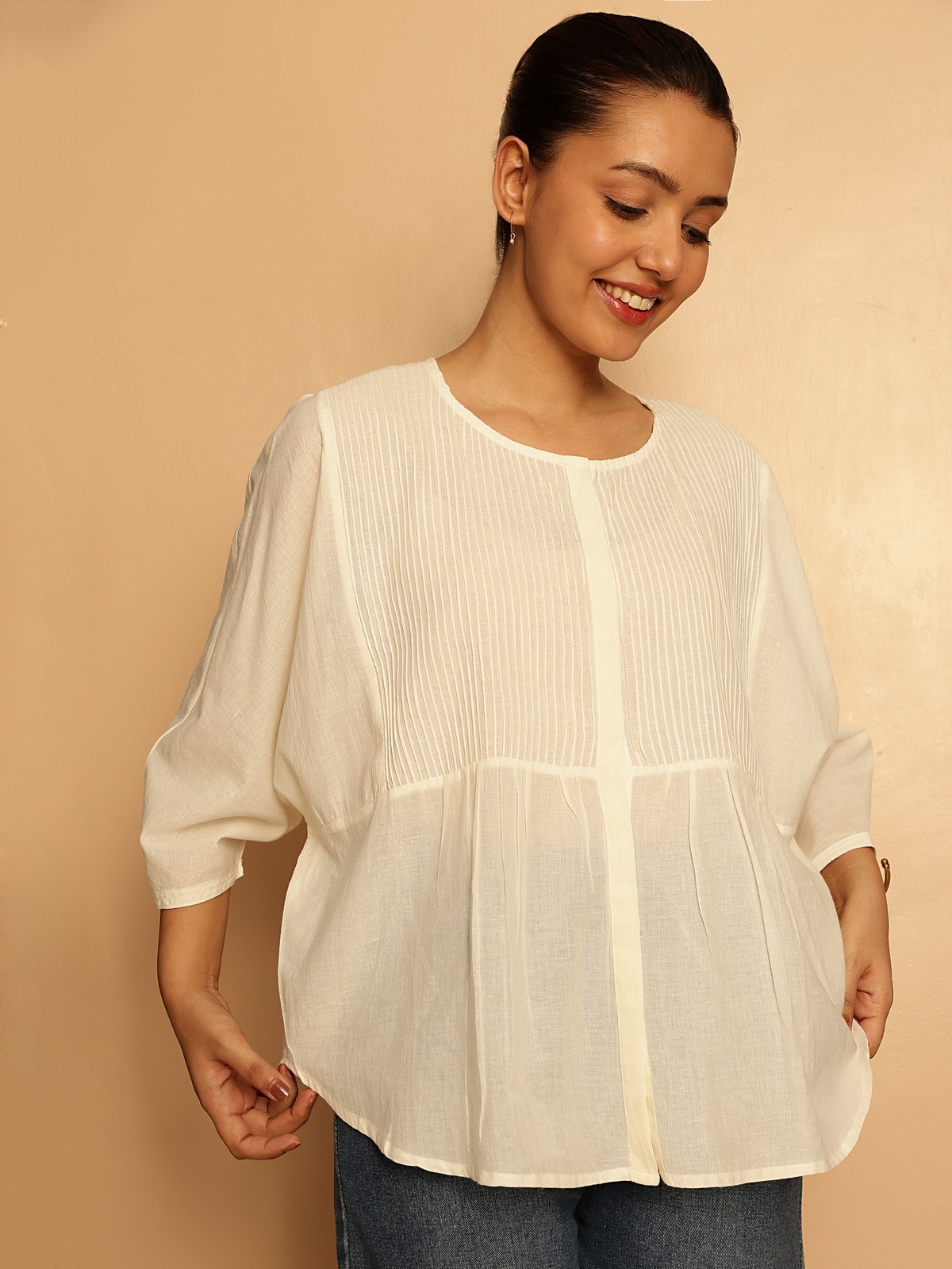 Angled view of white cotton hand-spun top highlighting natural fabric fall