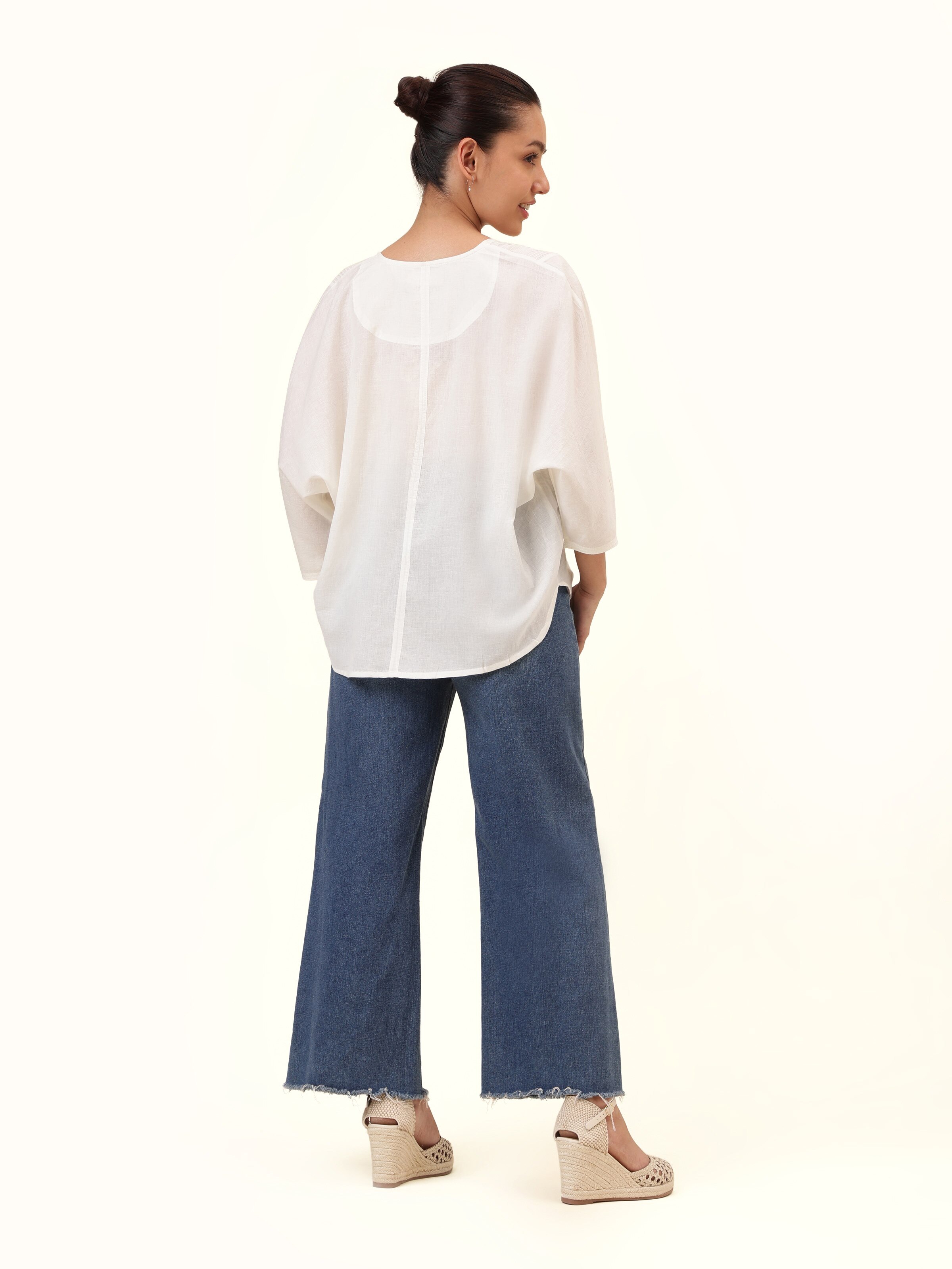 Back view of white cotton hand-spun top with clean minimal design