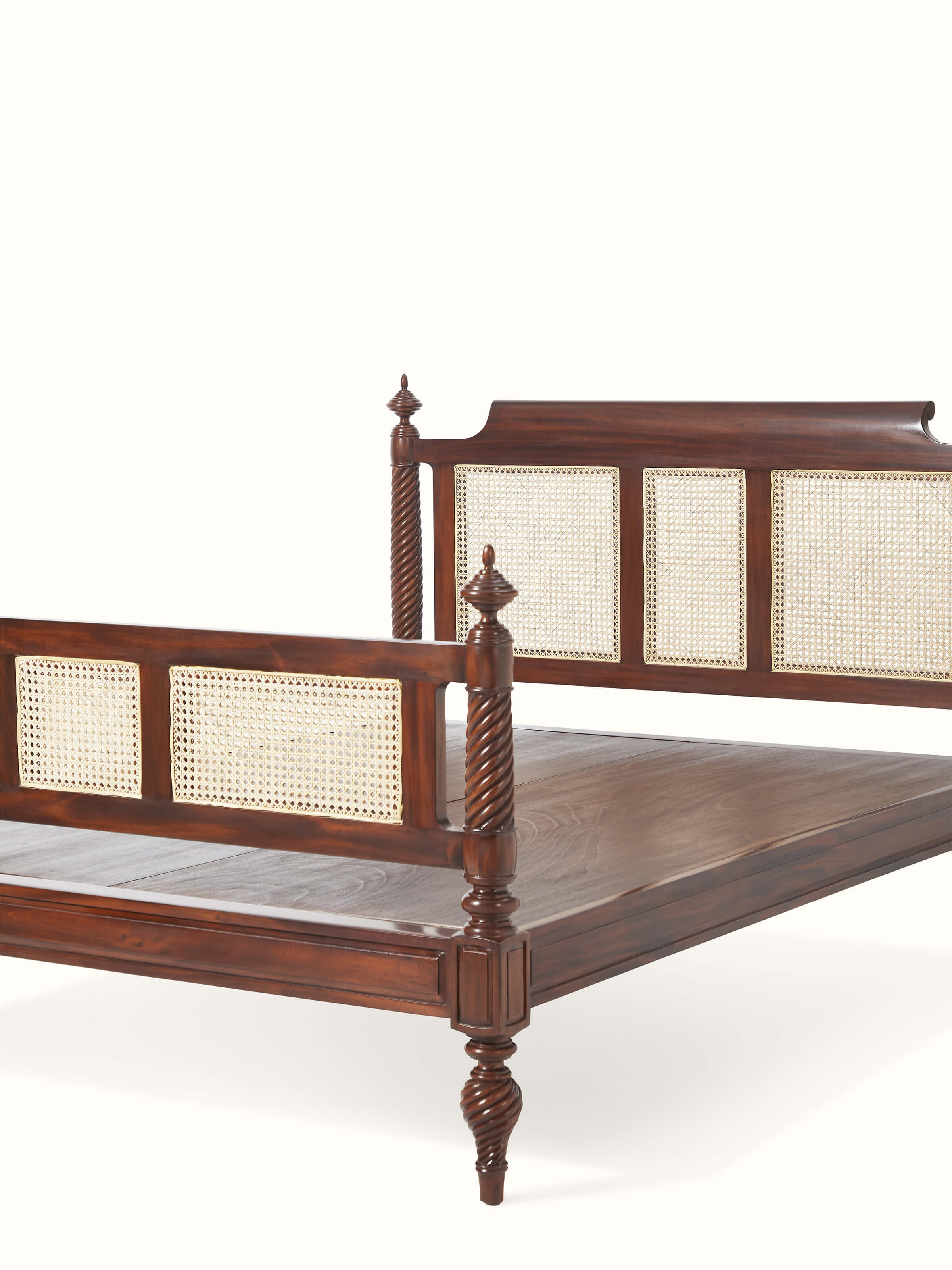 Close-up view of the carved mahogany wood detailing on the queen size bed, focusing on the craftsmanship and cane accents.