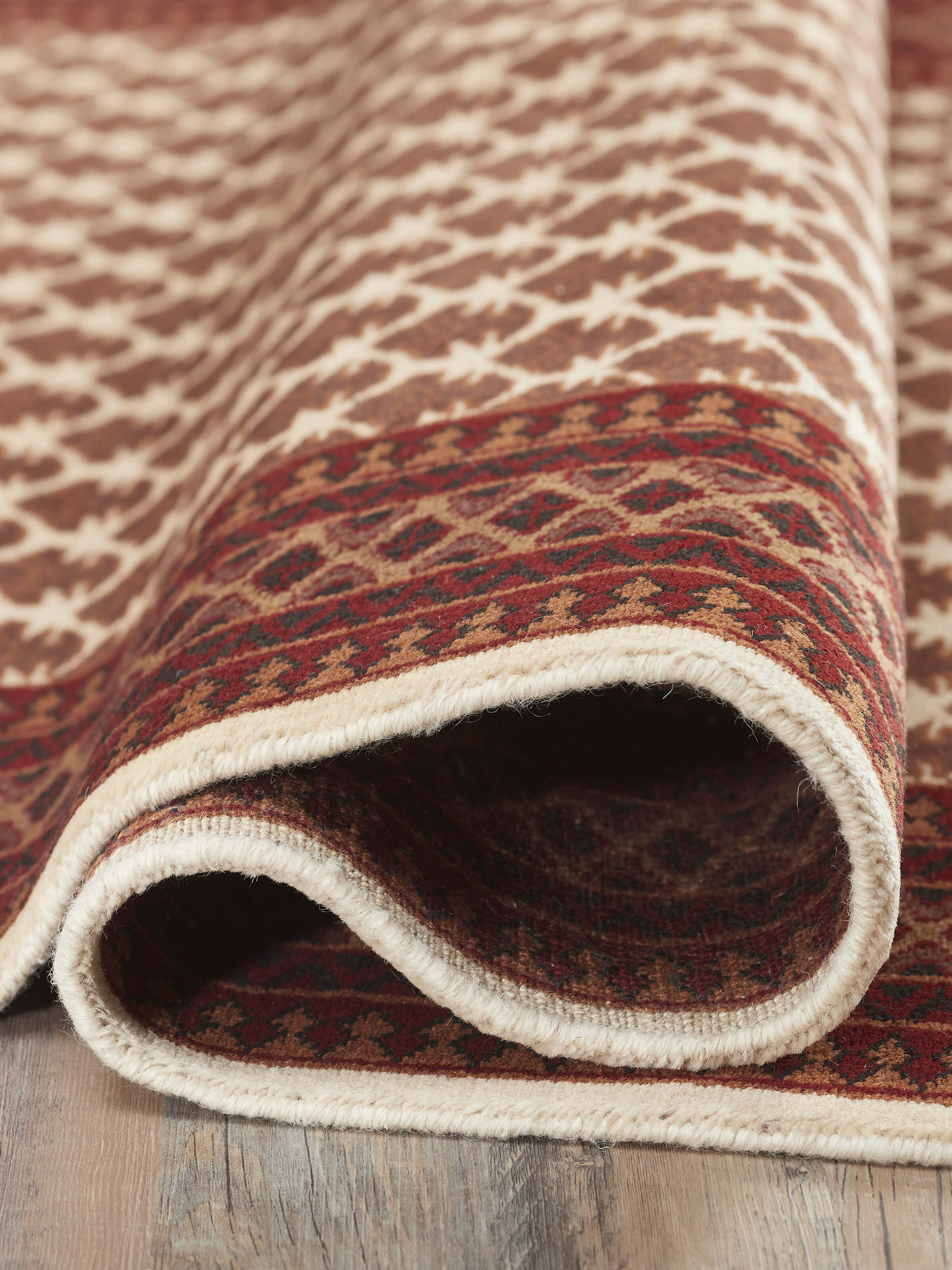 Traditional Lichi Ivory Rust Gwalior wool hand-knotted rug folded, showcasing its texture and color.