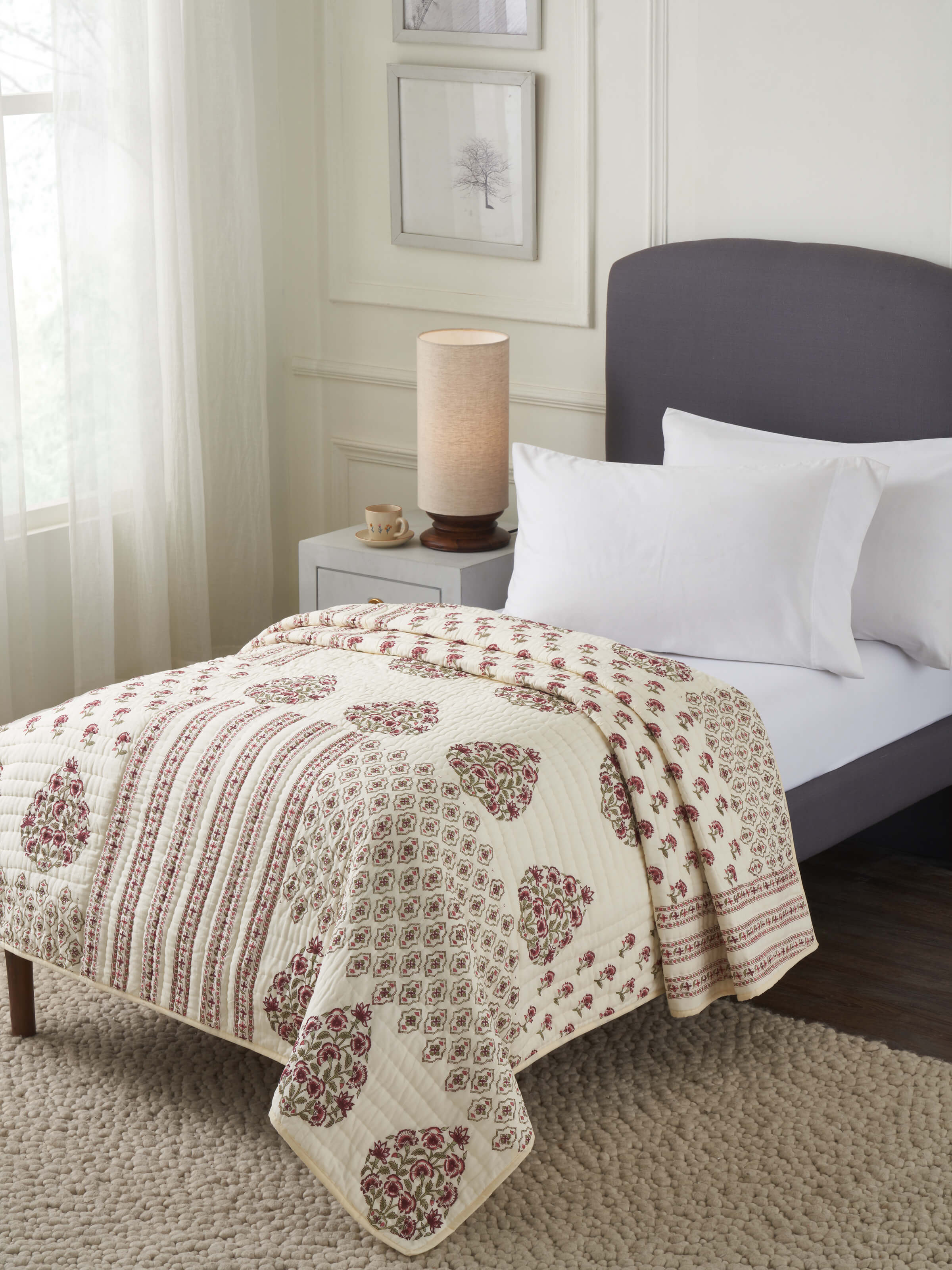 Aarunya red floral cotton Sanganeri block printed double quilt displayed on a bed, highlighting its vibrant floral design