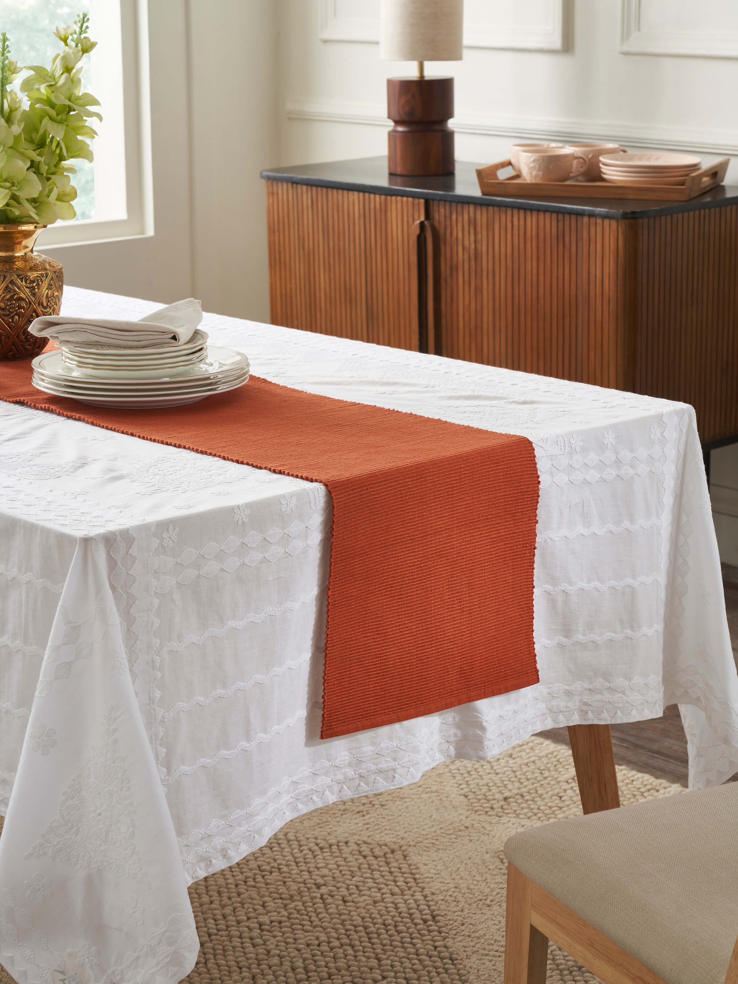 Lifestyle view of Vastav Rust Table Runner on a wooden dining setup, highlighting its earthy hue.