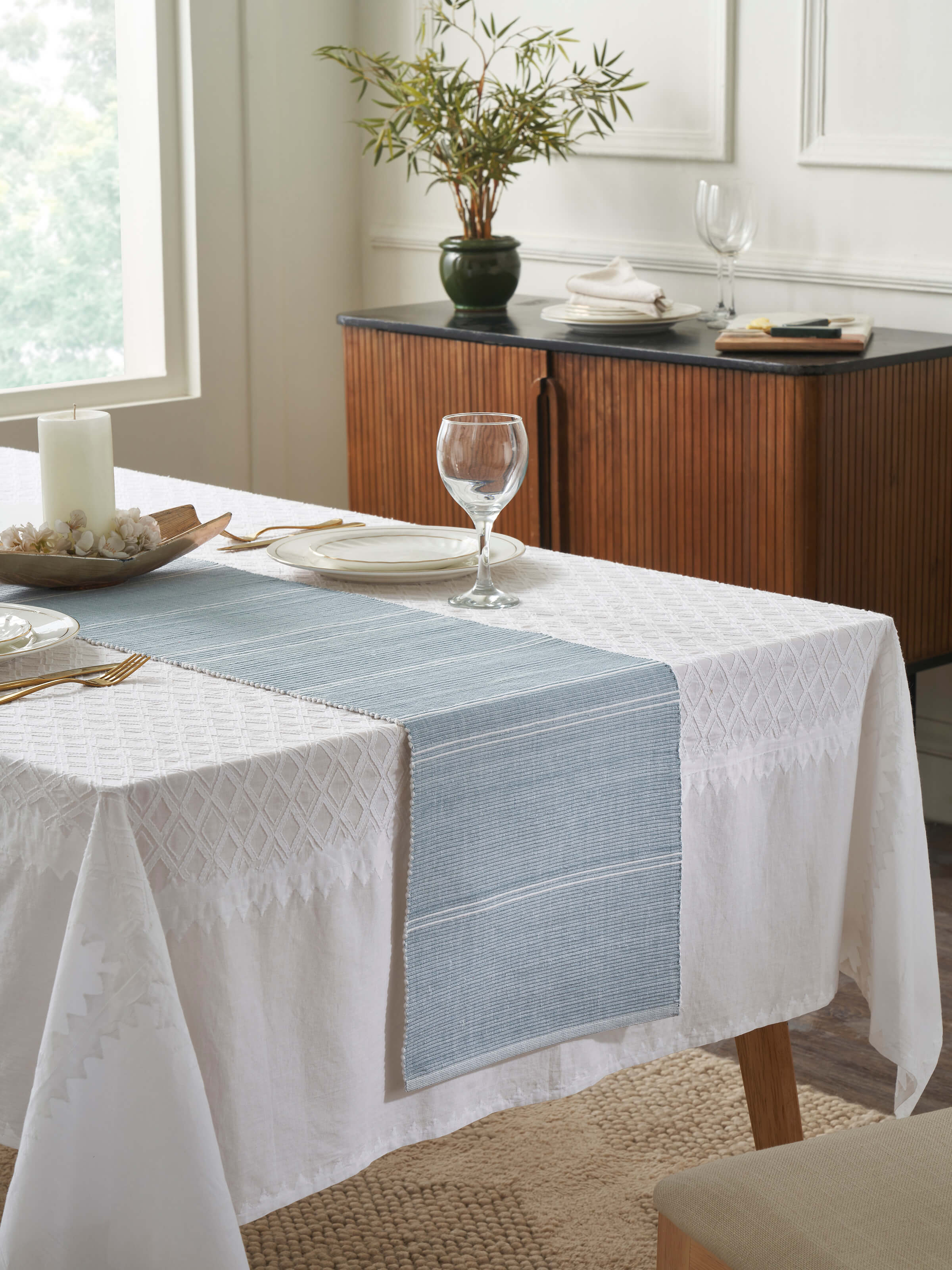 Lifestyle shot: Styled dining table with light blue striped cotton runner enhancing a minimal setting.