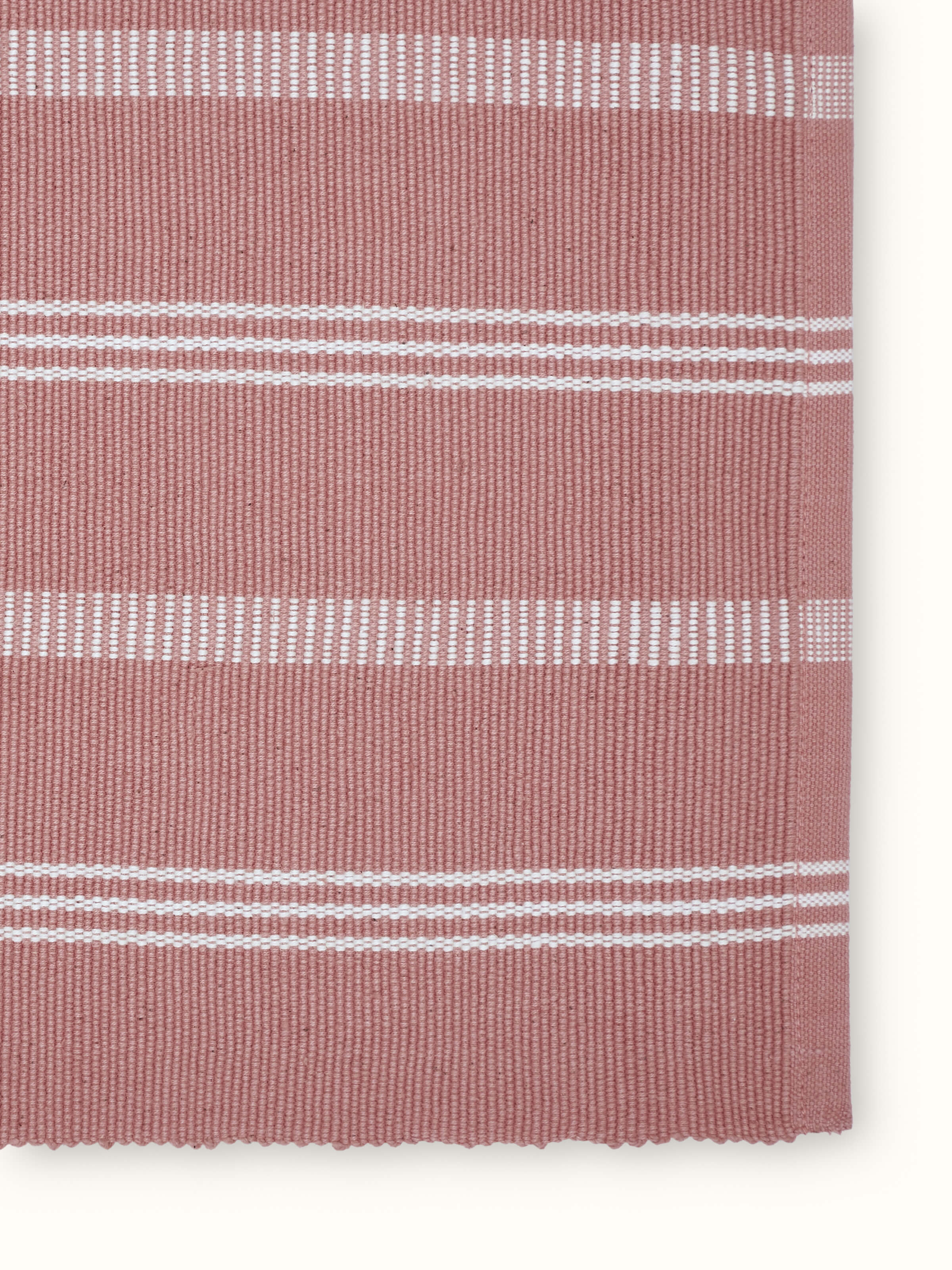 Angled view of Vastav pink striped cotton table mats highlighting woven texture