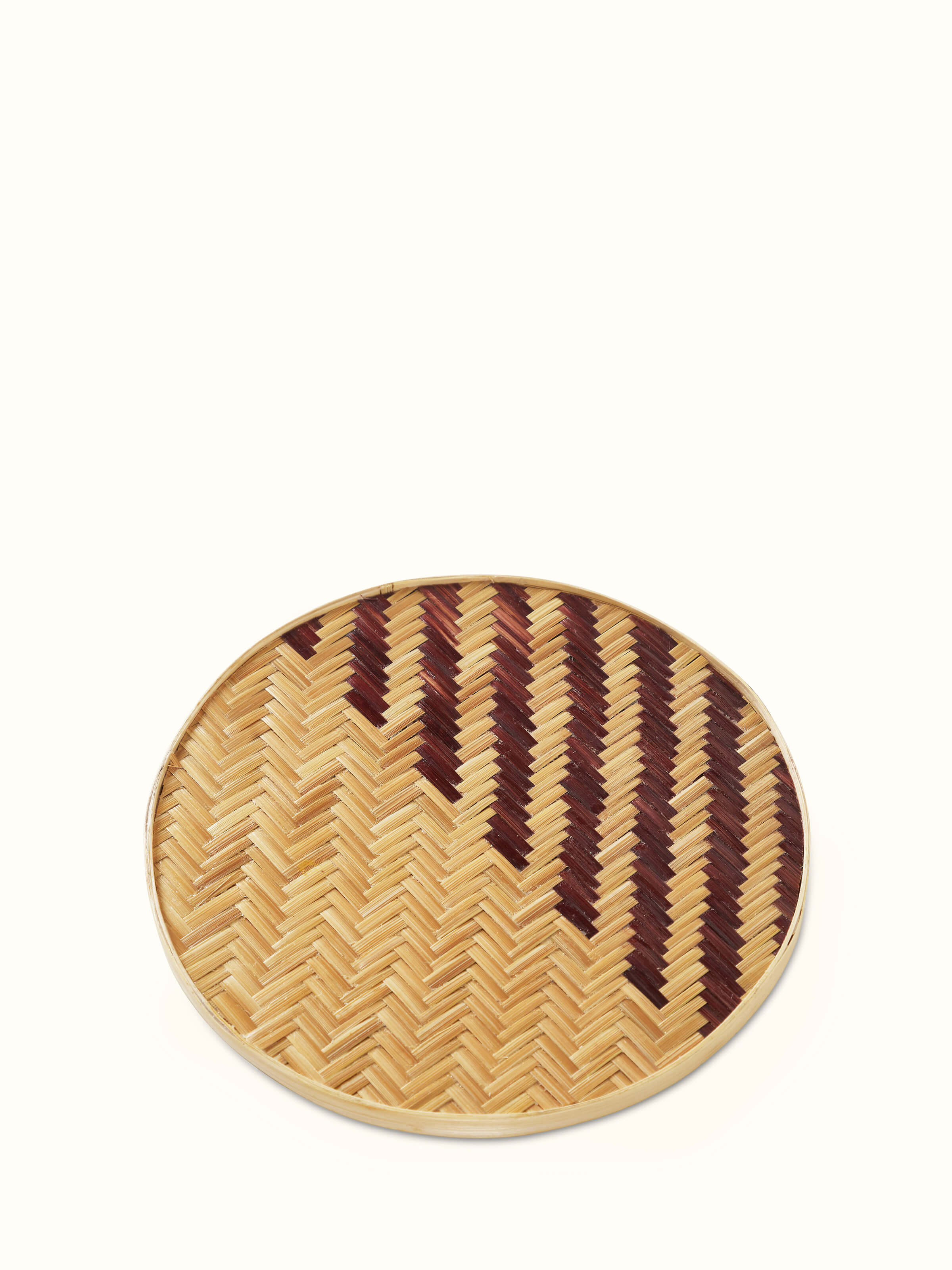 Naveena brown geometric round natural fibre trivet, displaying the trivet in use with a pot or dish