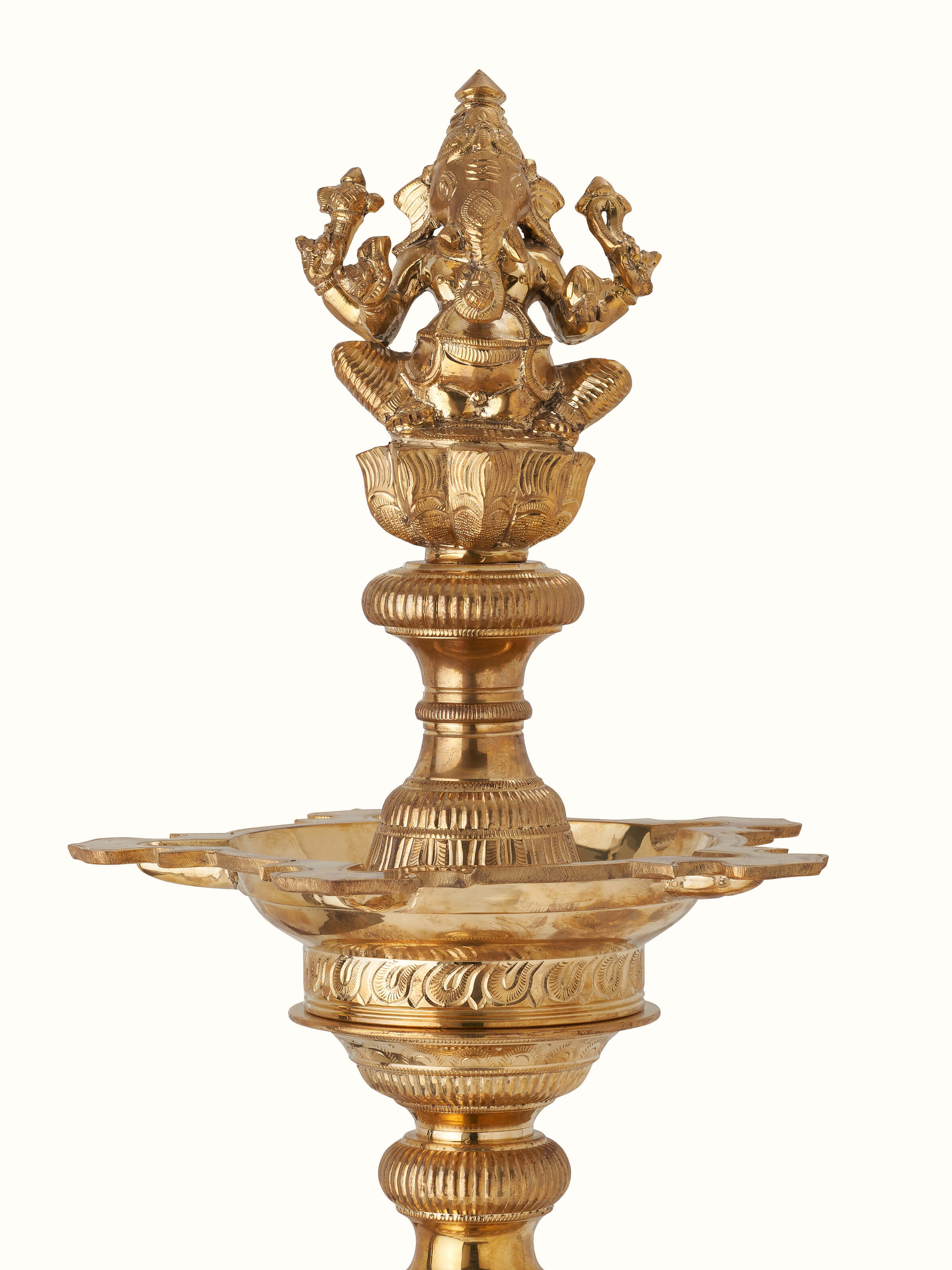 Detailed close-up of polished brass Vilakku stand diya focusing on intricate patterns