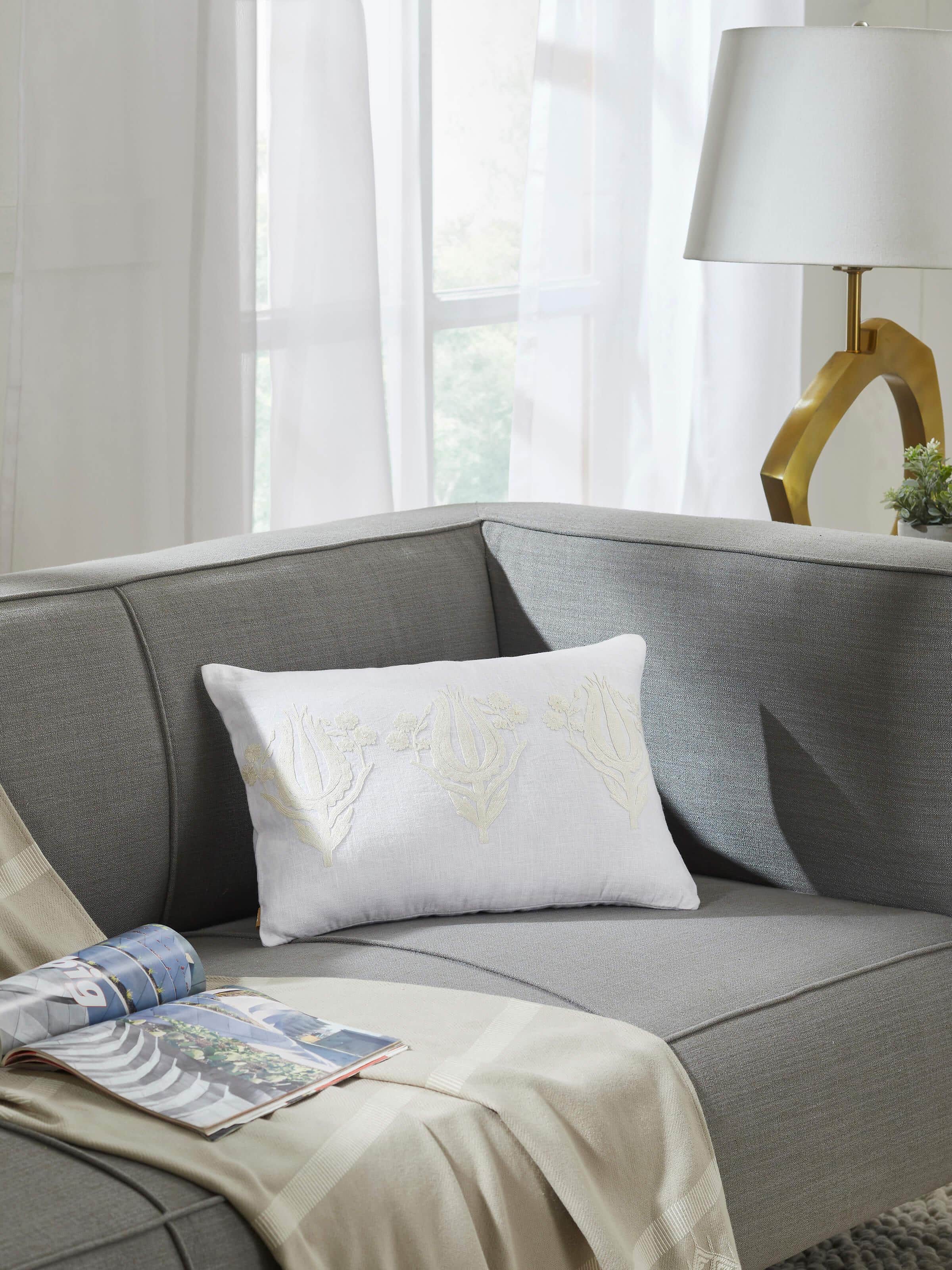 Side view of embroidered cushion cover placed on beige sofa setting