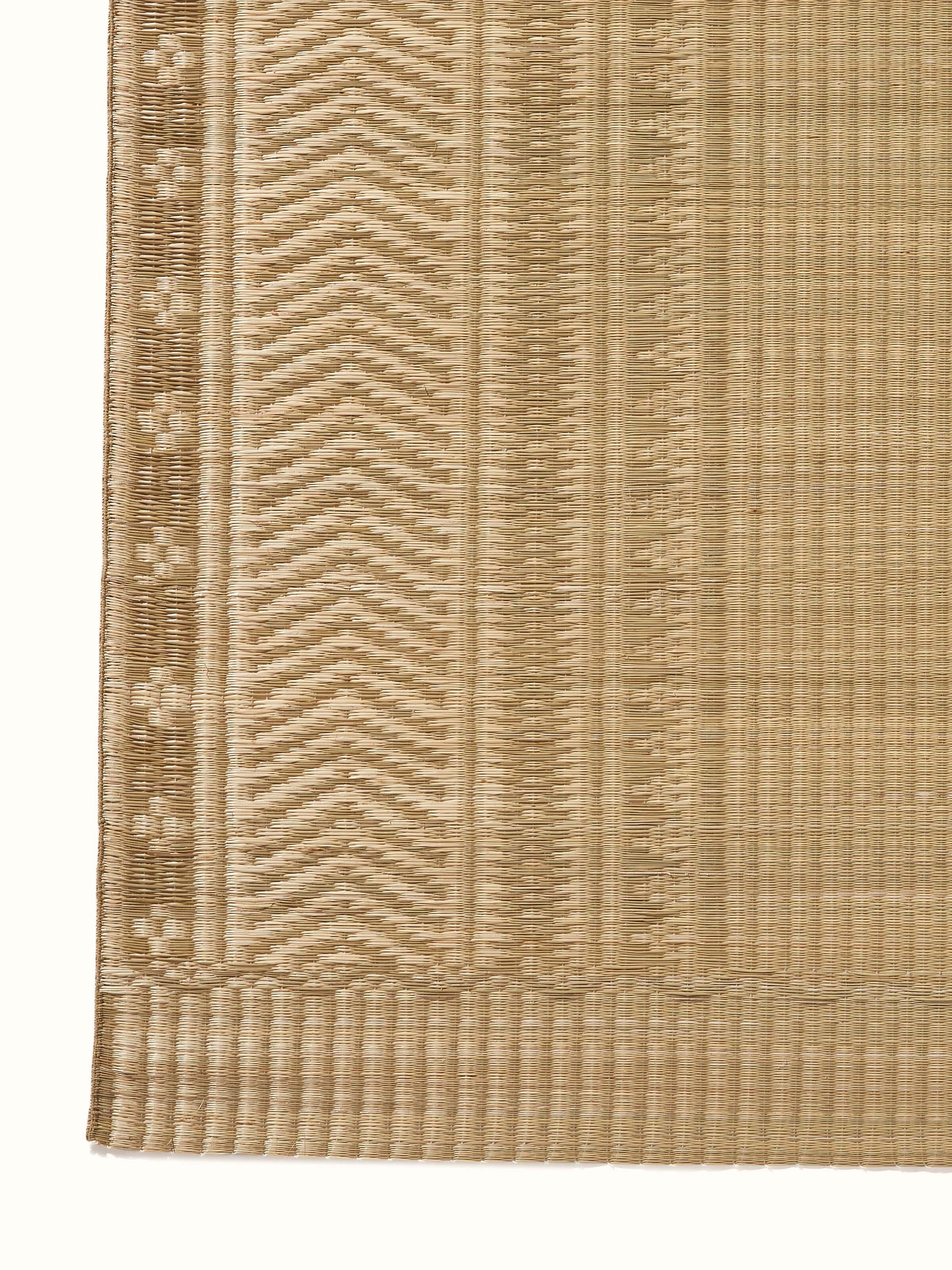 Angled view of Folk geo beige West Bengal madurkathi natural fibre mat showing its design and usability.
