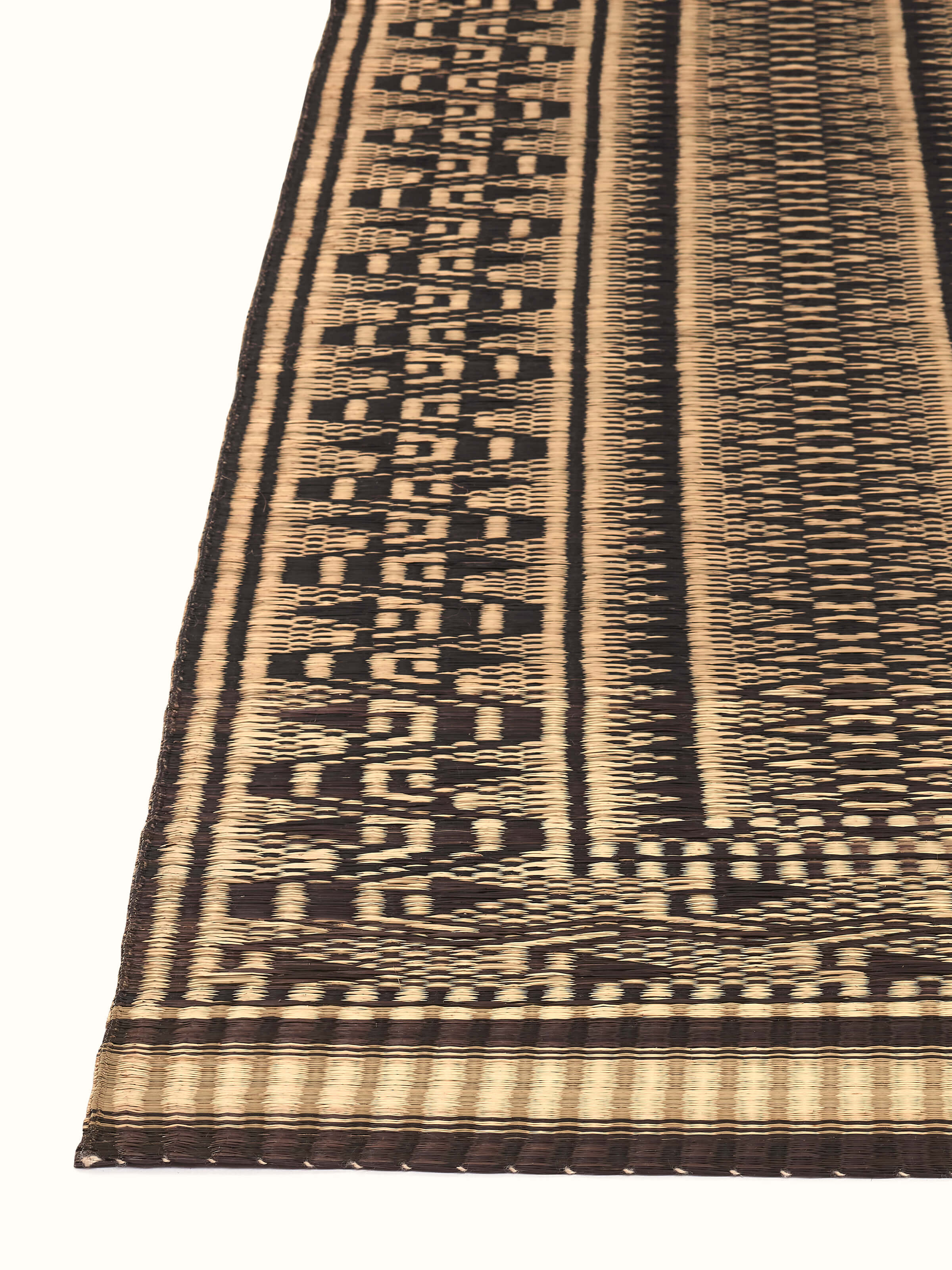 Angled view of Folk Geo Black West Bengal Madurkathi Natural Fibre Mat highlighting the texture and pattern details.
