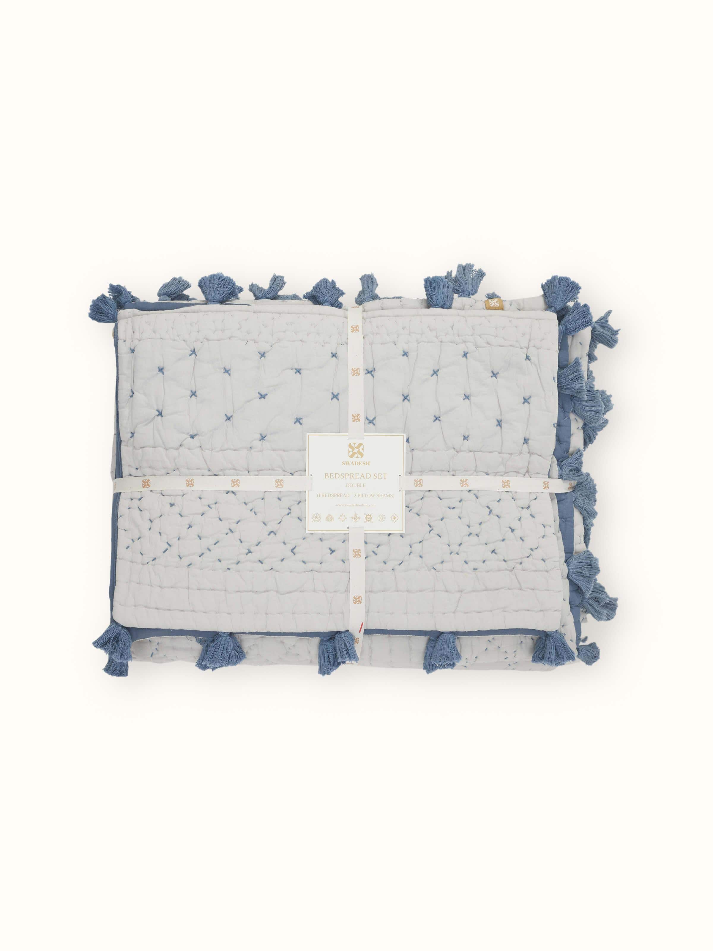 Nitya Blue Textured Stripe Cotton Razai Embroidered Double Bedspread Set displayed on a bed, featuring its striped pattern.